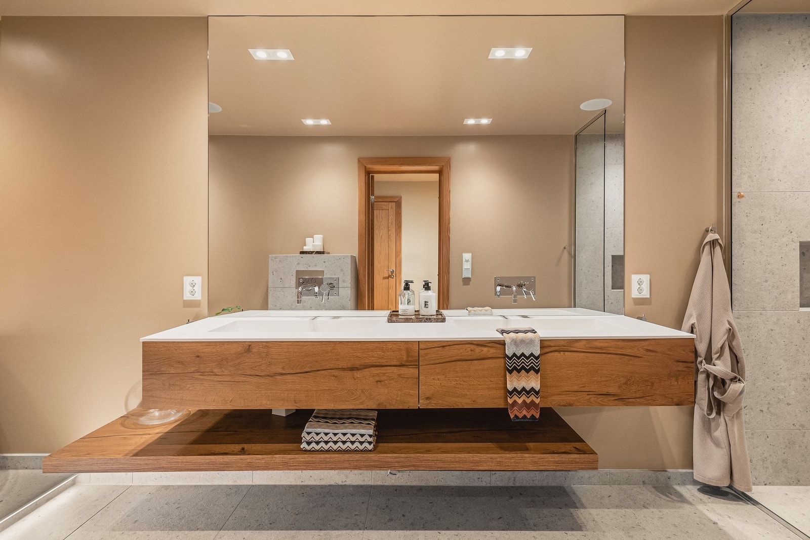 Badet har glassvegger i dusjnisje, badekar, veggtoalett og baderomsinnredning med heldekkende servant samt belyst speil. Galleribilde