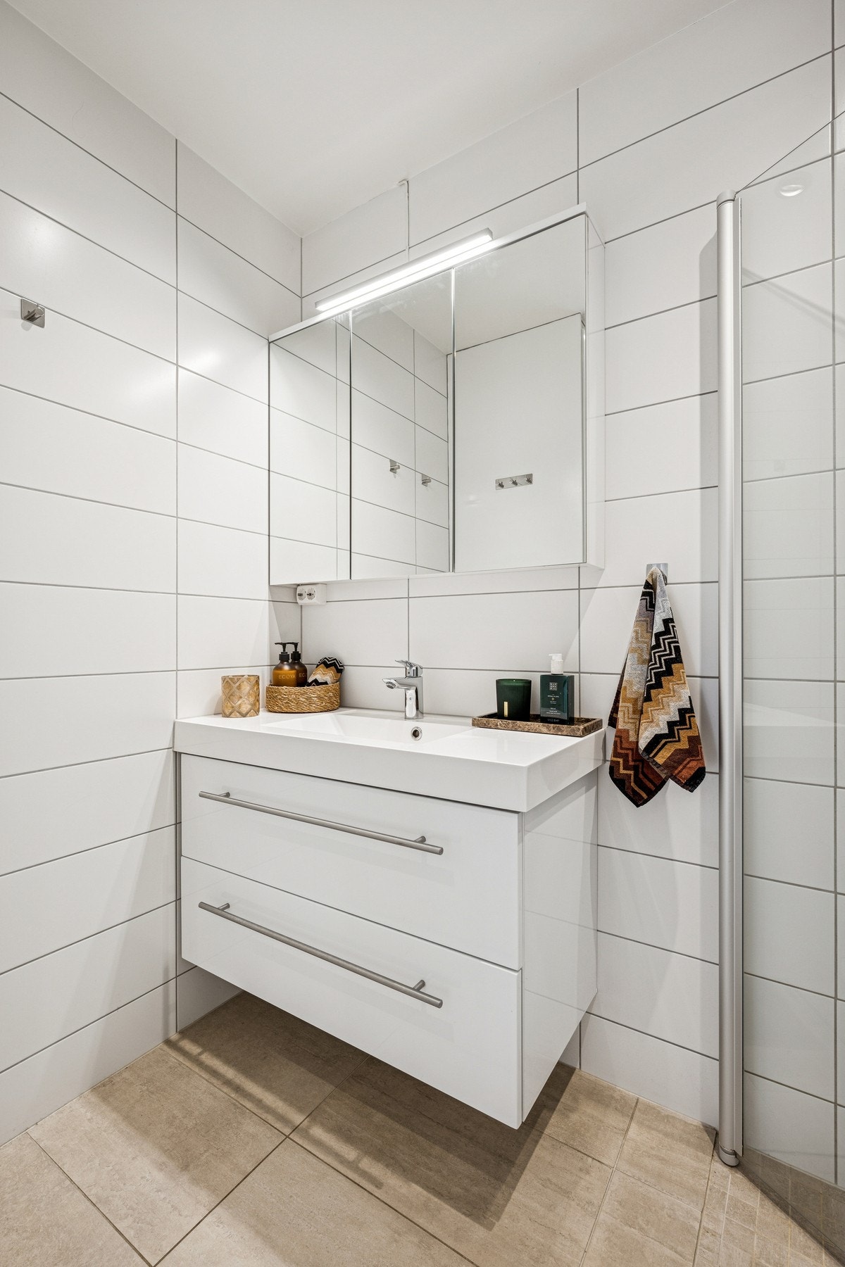 Moderne servantinnredning med glatte fronter, heldekkende servant og speilskap med belysning - god oppbevaring i et rent og ryddig rom. Galleribilde