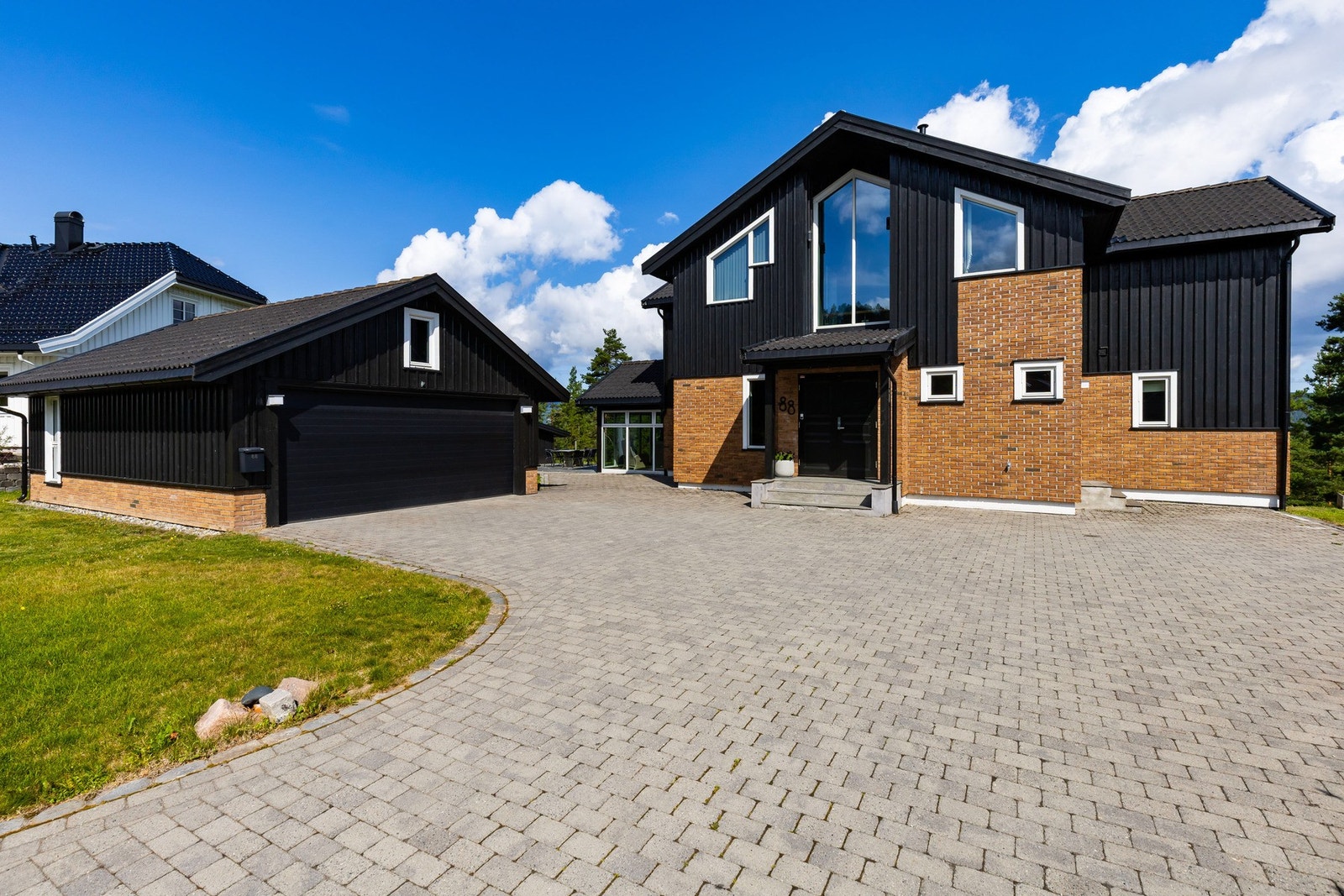 Inngangen står i stil til huset for øvrig, med skifertrapp, ringeklokke og tofløyet ytterdør holdt i sort. Parkering i dobbelgarasje og i egen gårdsplass. Galleribilde