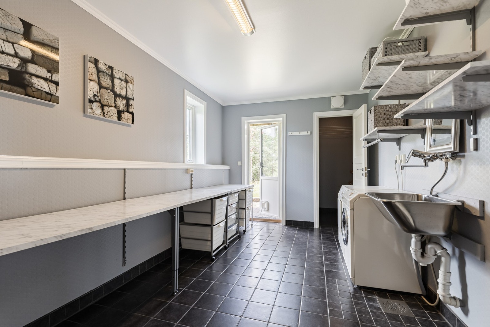 Vaskerommet har flislagt gulv og praktisk utgang til eiendommen. Galleribilde