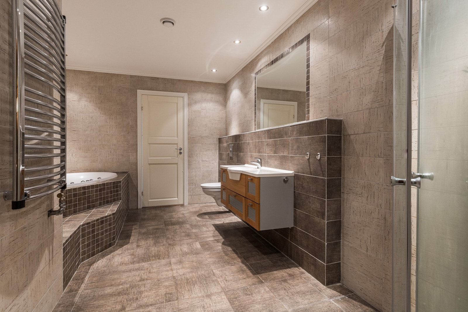 Rommet er kledd med grå fliser, og badet har gulvvarme, håndkletørker og vegghengt toalett. Galleribilde