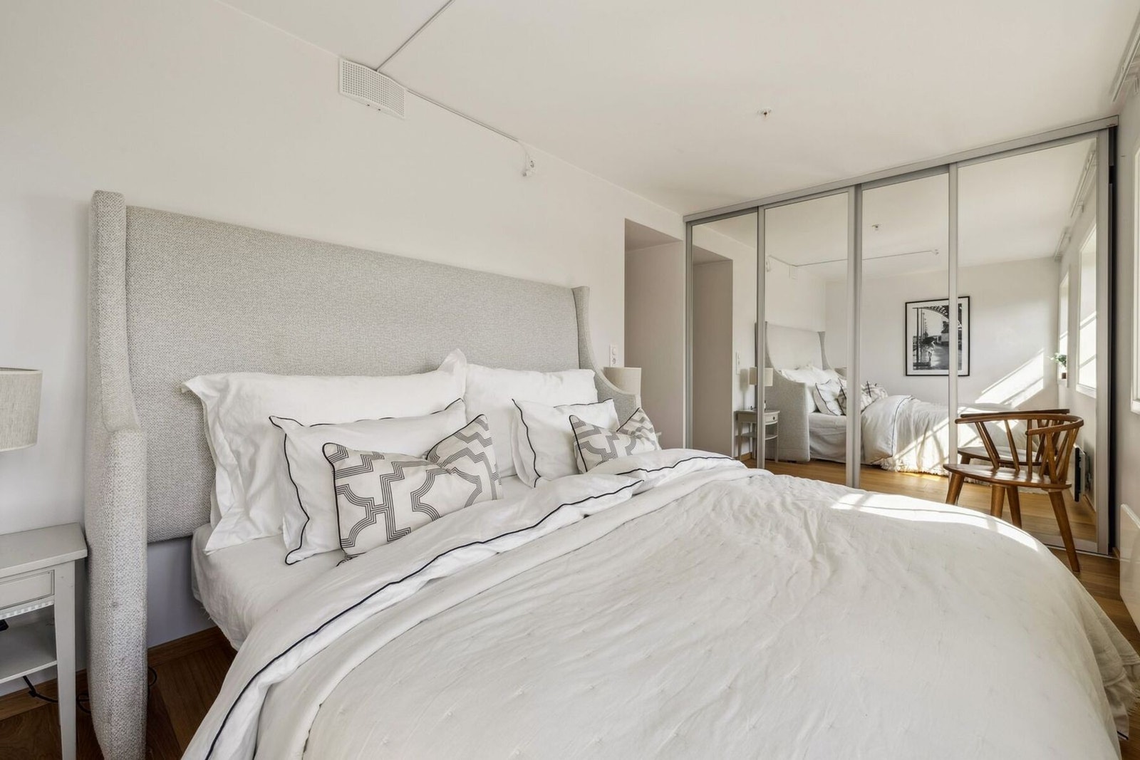 En stor og praktisk skyvedørsgarderobe med speilfronter sørger for rikelig med oppbevaringsplass samtidig som den bidrar til en romslig og luftig følelse i rommet. Galleribilde