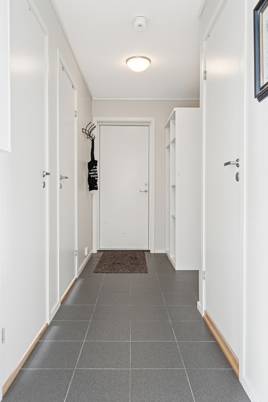 Du ønskes velkommen inn i en hyggelig flislagt entrè som er utstyrt med et åpent garderobeskap Galleribilde