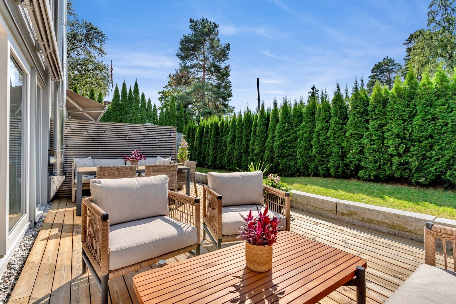 Høy hekk skjermet for innsyn, og terrassen er avdelt med levegg mot nabo. Galleribilde