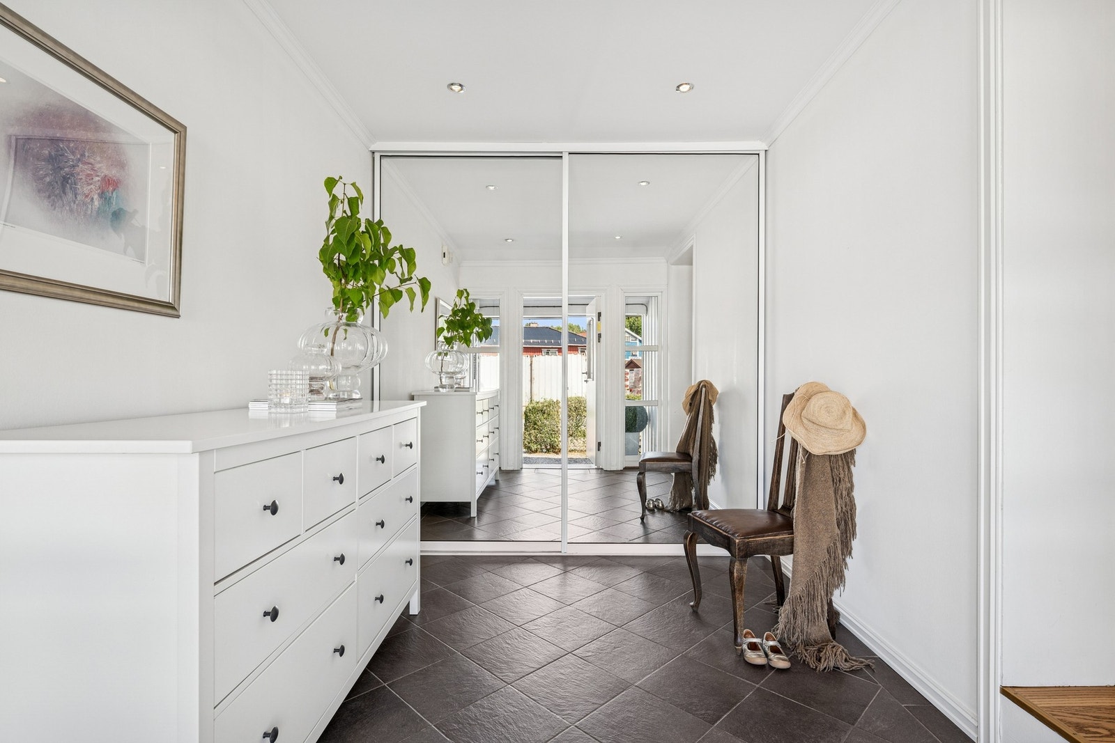 Stor entré med flislagt gulv og integrert skyvedørsgarderobe med speil - perfekt for oppbevaring av yttertøy og sko. Et elegant førsteinntrykk for både deg og gjestene dine. Galleribilde