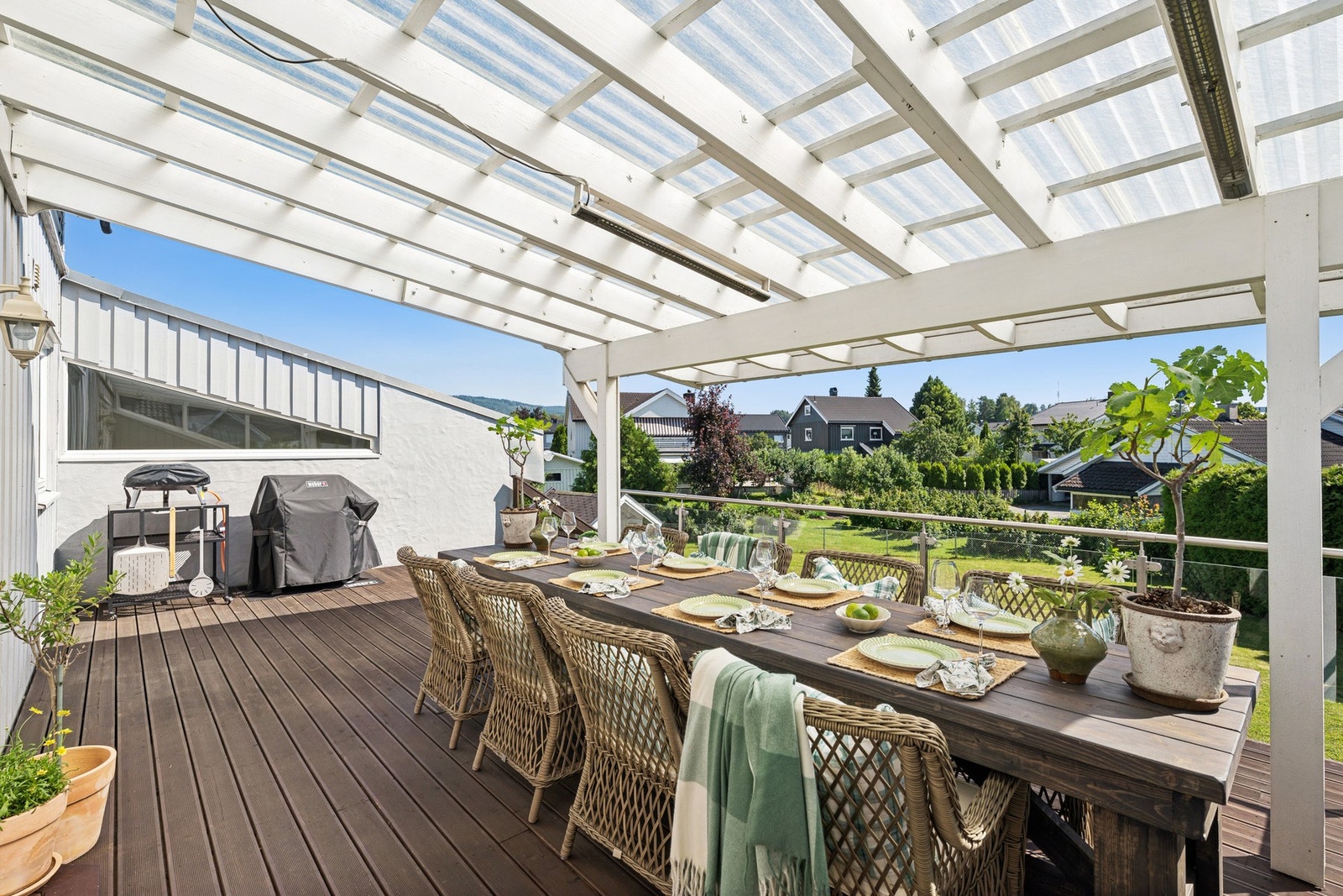 Stor, overbygget terrasse med god plass til spisegruppe og grill. Her kan måltidene nytes i ly for både sol og regn - med utsikt over hage og grønne omgivelser. Galleribilde