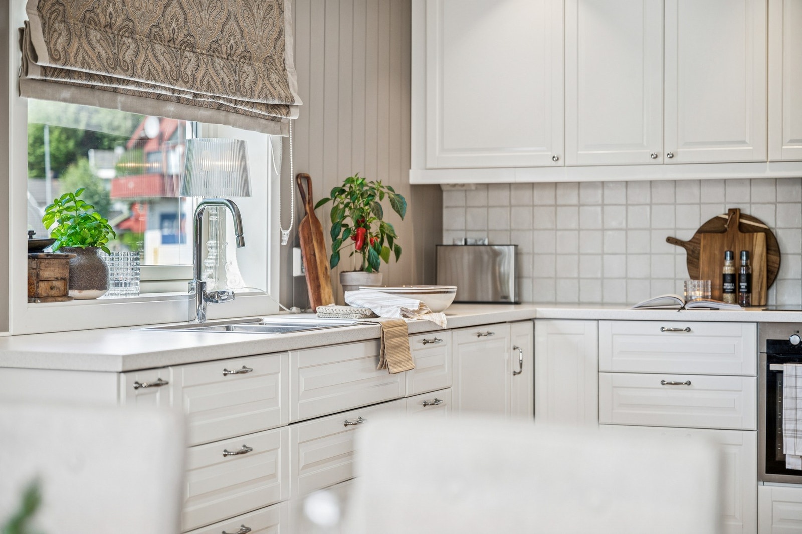 Kjøkkenet er utstyrt med laminat benkeplate, dobbel kum og kjøkkenventilator med avtrekk ut. Vinduet over benken gir rikelig med dagslys og utsikt mot hagen. Galleribilde