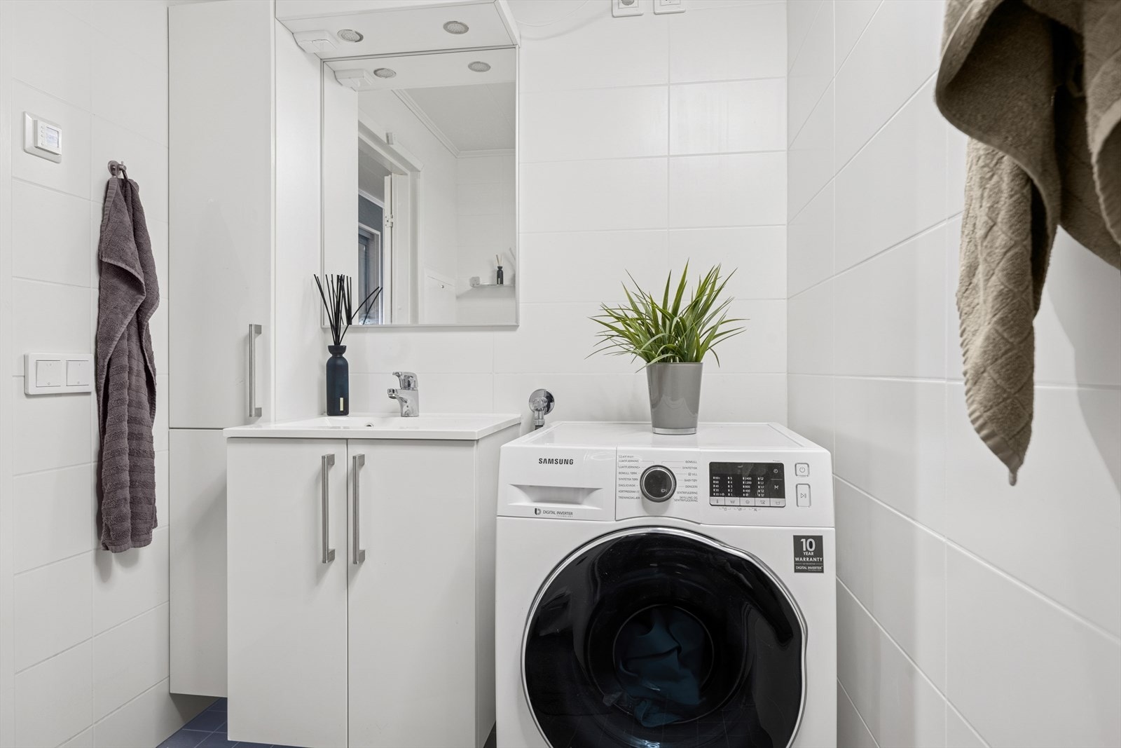 Lys baderomsinnredning med mye oppbevaringsplass. Opplegg for vaskemaskin. Galleribilde