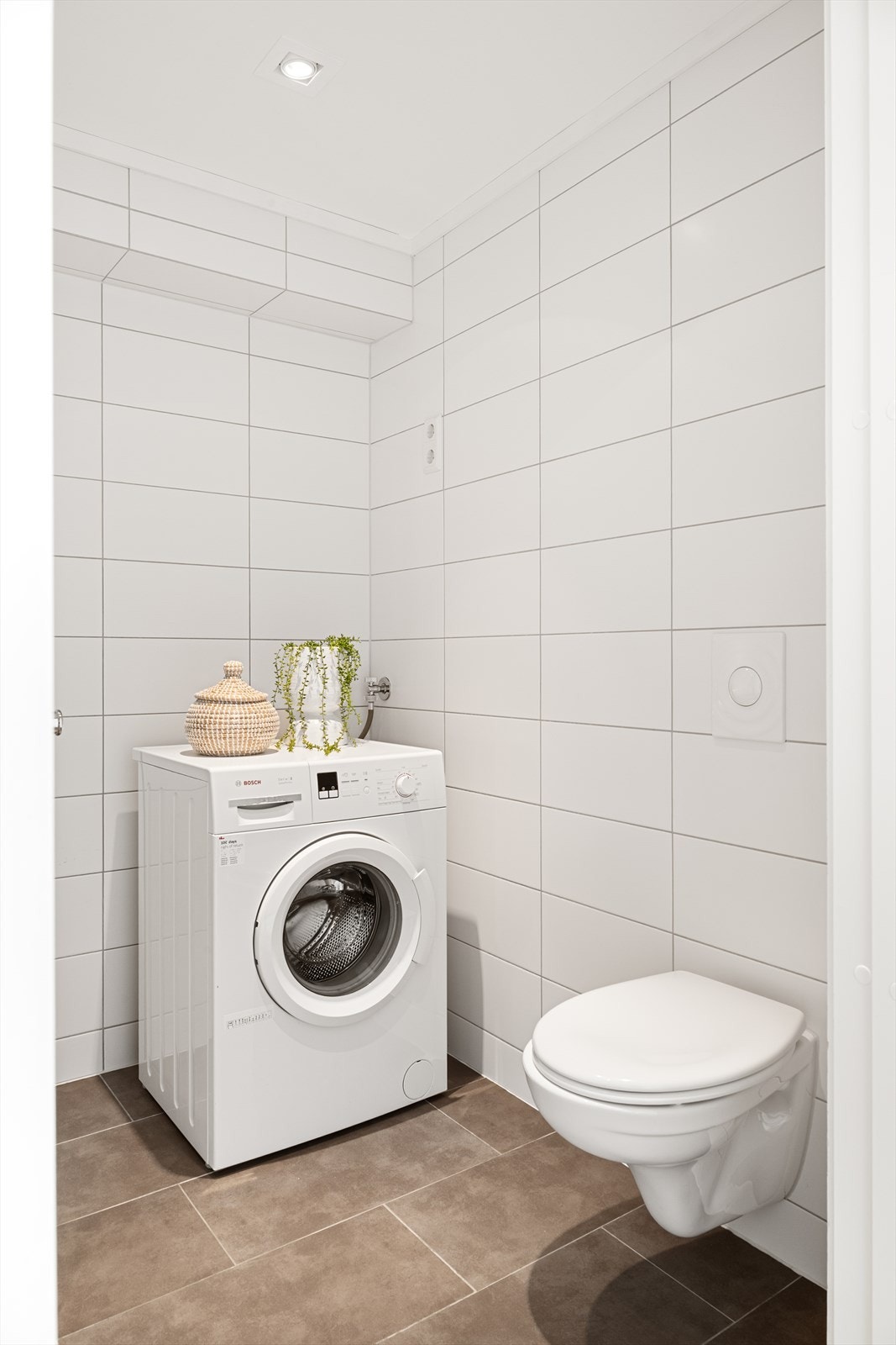 Badet er innredet med servant i baderomsmøbel, veggmontert toalett og dusjhjørne. Galleribilde