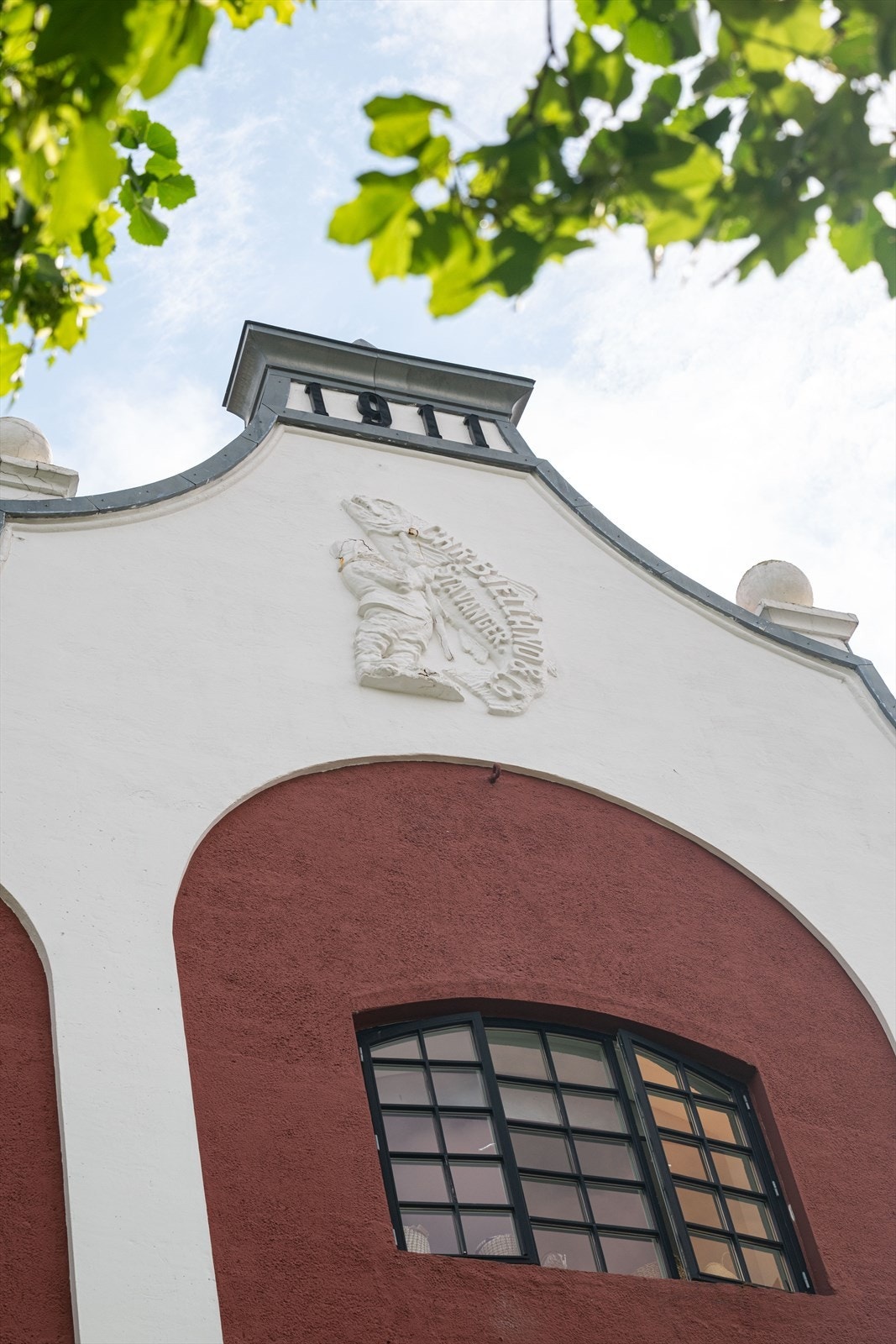 Firmaets varemerke Manden med fisken , tegnet av Theodor Kittelsen, i gavlen mot vest. Galleribilde