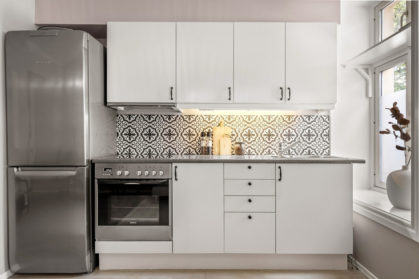 Lyst, tidløst kjøkken med stilige fliser på vegg. Galleribilde