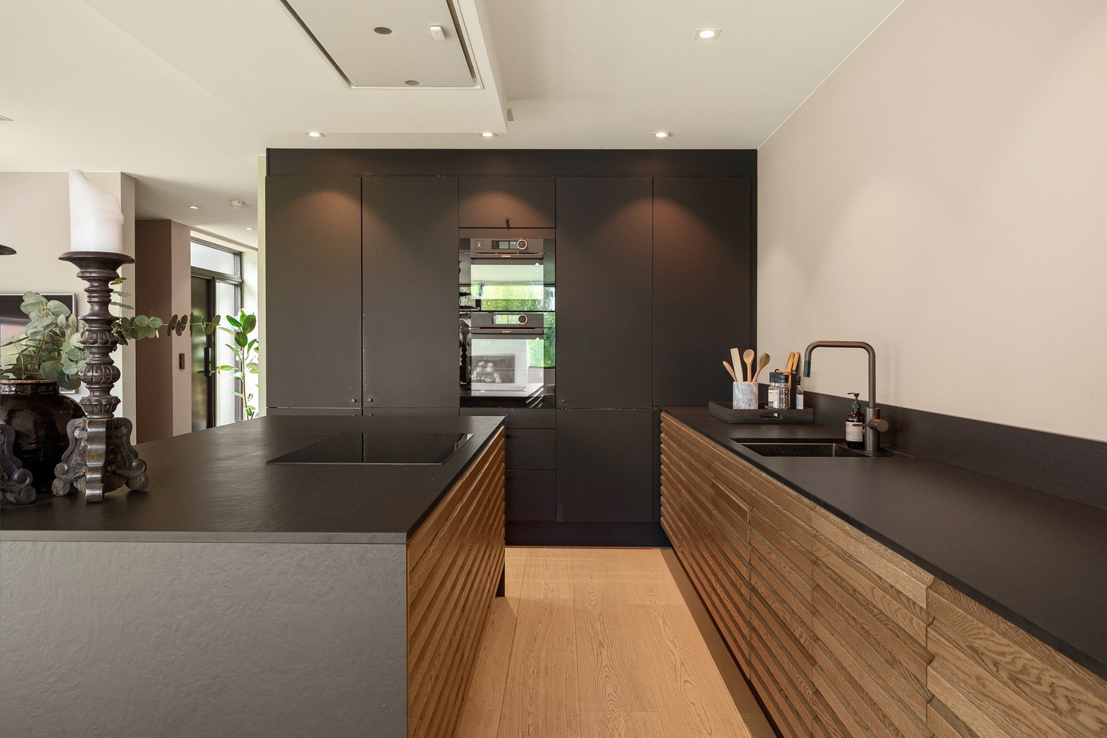 Kjøkken med integrerte hvitevarer og gjennomførte materialvalg. Galleribilde