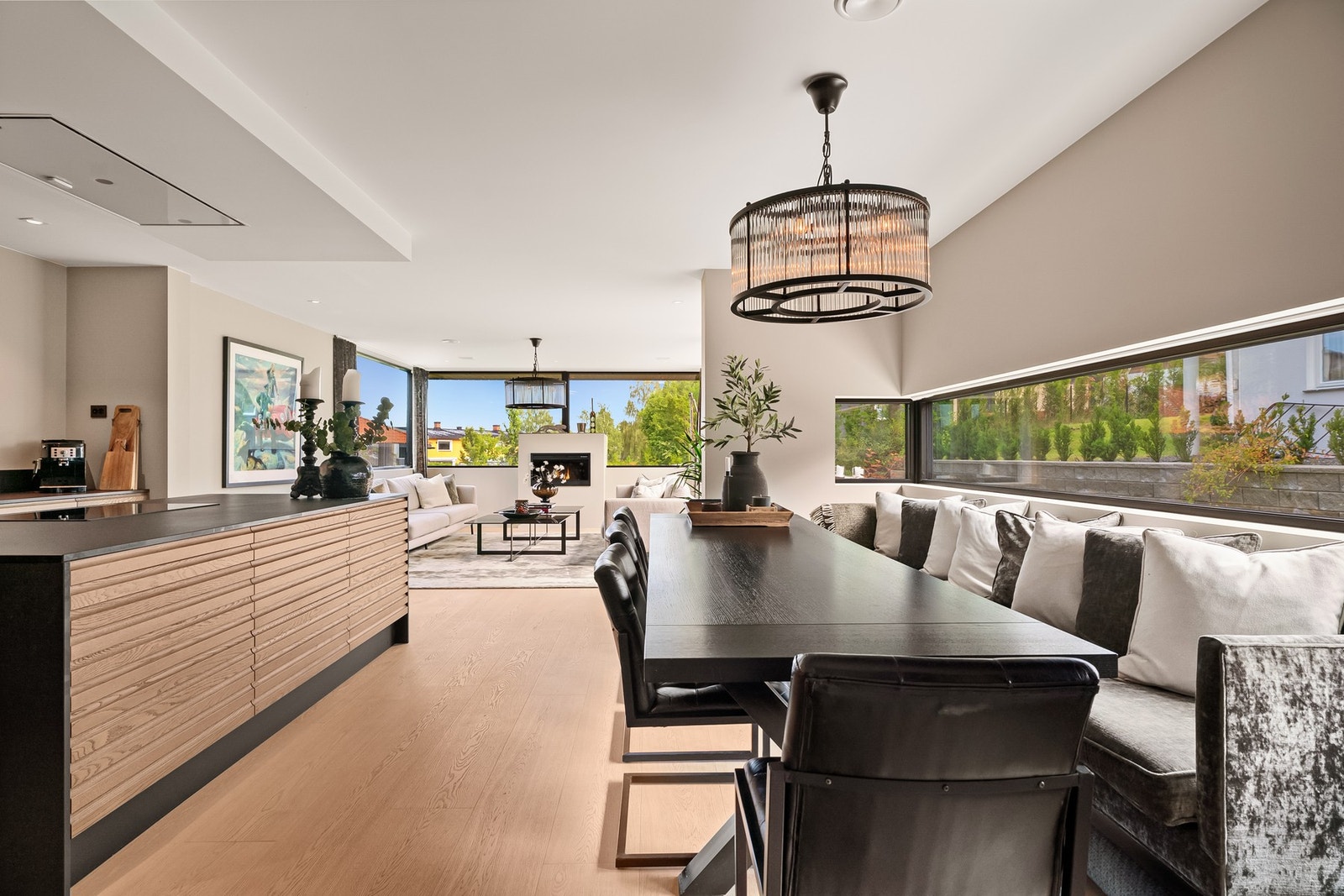 Åpen og sosial sone med eksklusivt kjøkken, stor spiseplass og innbydende stue med elektrisk peis. Galleribilde