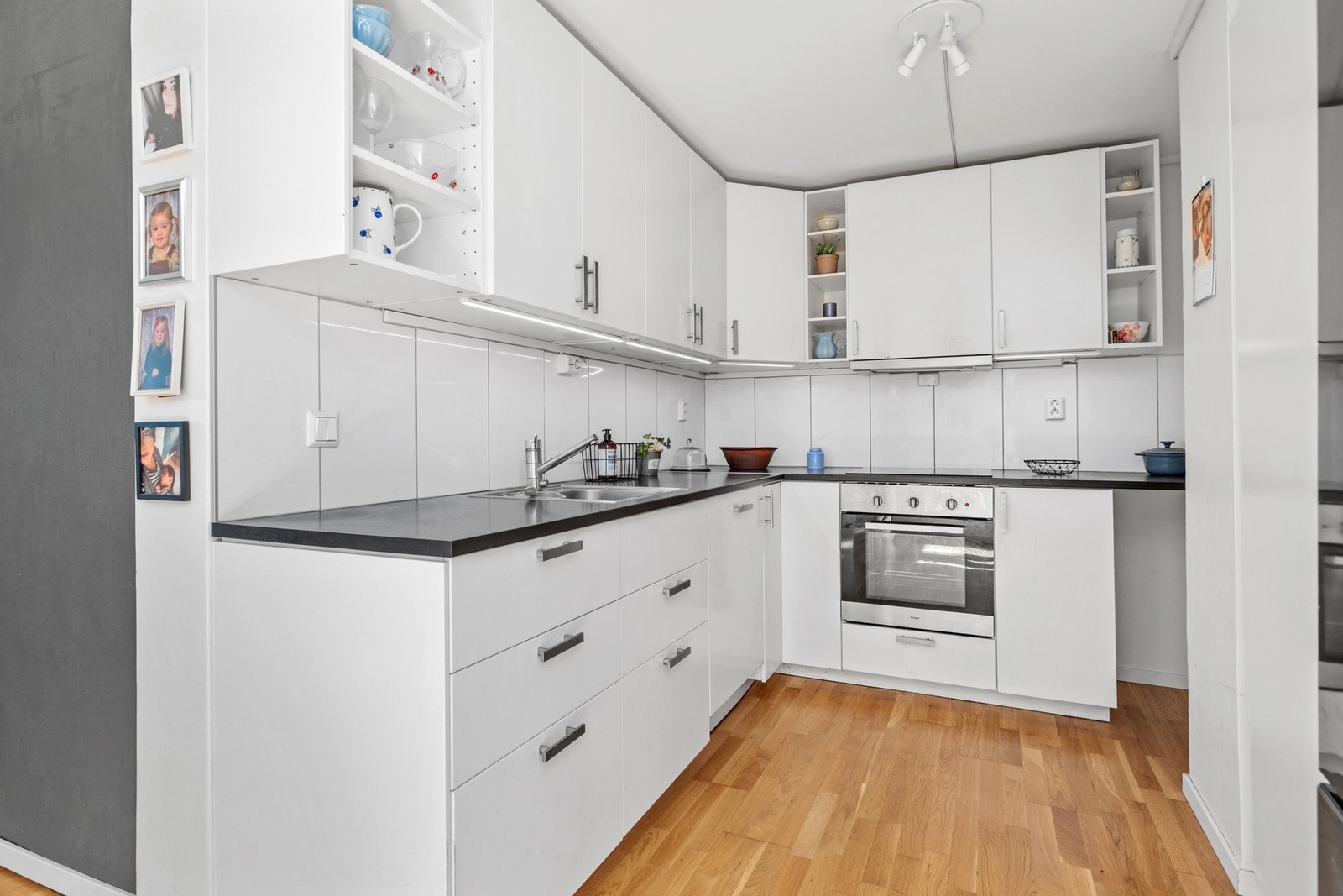 Kjøkken på 11,5 kvm utstyrt med integrerte hvitevarer som oppvaskmaskin, stekeovn, induksjonstopp og mikrobølgeovn. Galleribilde