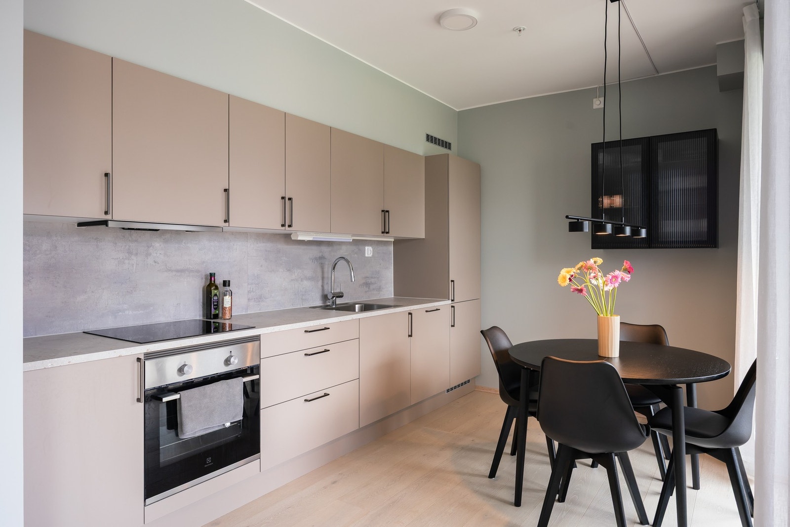 Moderne kjøkken med smakfull innredning og integrerte hvitevarer (kombiskap, komfyr, induksjonstopp og oppvaskmaskin). Galleribilde