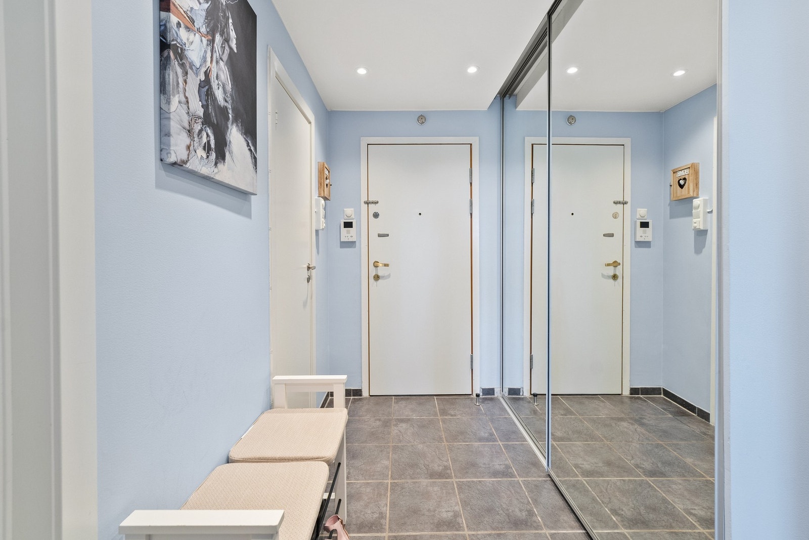 Leiligheten åpner med en lys og moderne entré med flislagt gulv, downlights i himling og skyvedørsgarderobe. Galleribilde