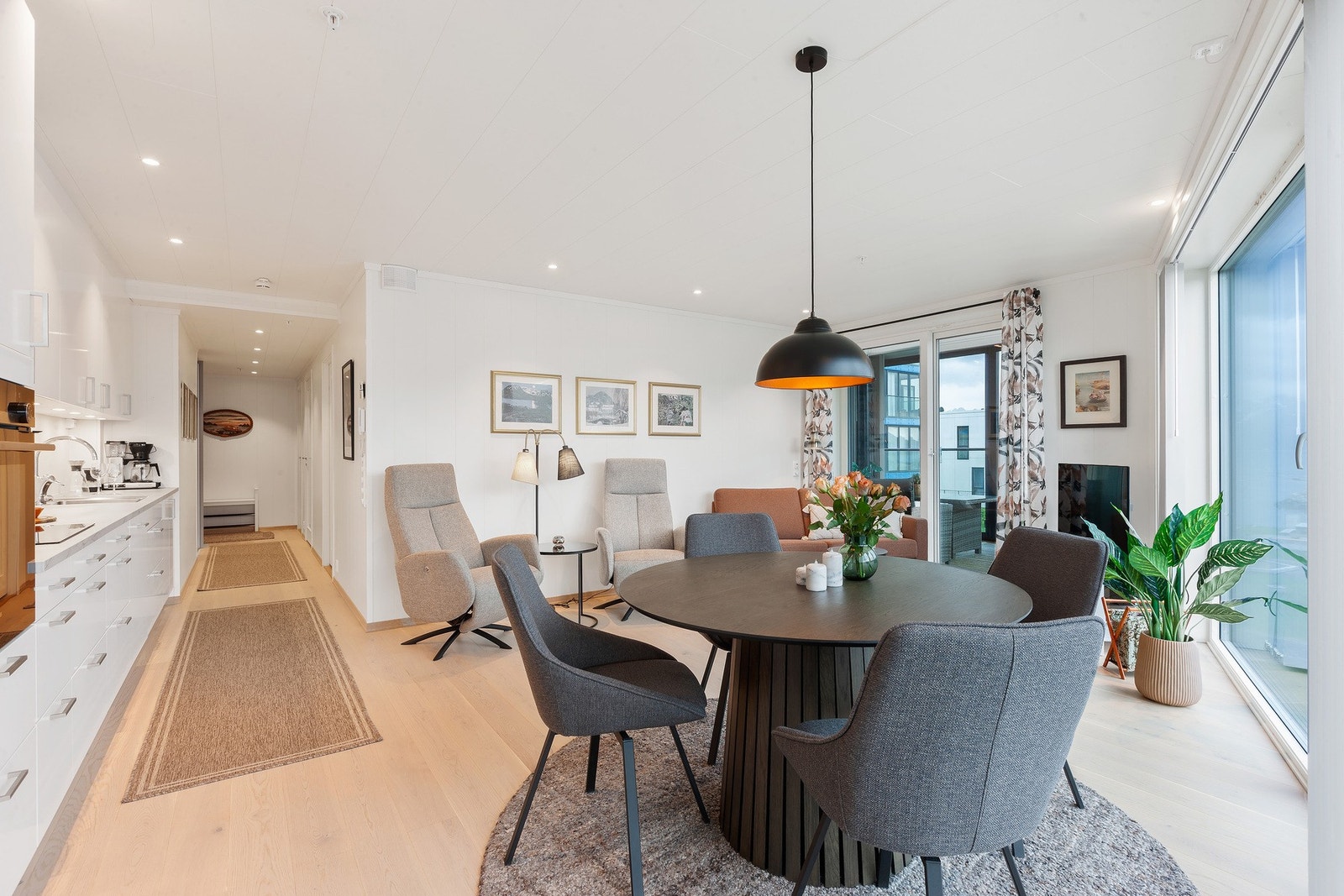 Åpen stue og kjøkkenløsning med dør ut til innglasset veranda som en forlengelse av oppholdsrommet. Galleribilde