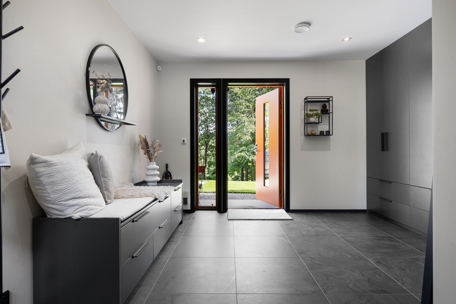 Langs venstre vegg ved inngangen finner du et stort, integrert garderobeskap i svart utførelse - en praktisk og stilren oppbevaringsløsning som bidrar til å holde entréen ryddig og funksjonell. Galleribilde