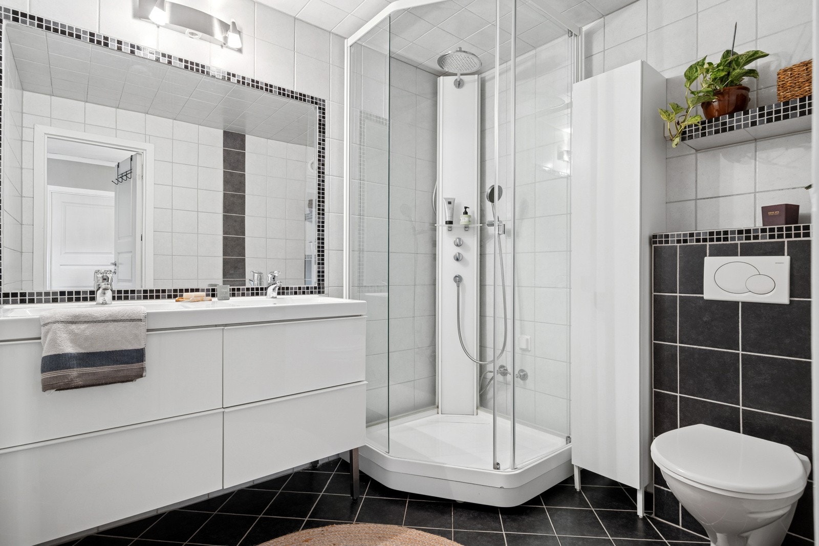 Det 4,5 kvm store badet har flislagte overflater og behagelig gulvvarme. Badet er utstyrt med en pen baderomsinnredning med skuffeseksjoner, dobbel servant, dusjkabinett og toalett. Galleribilde