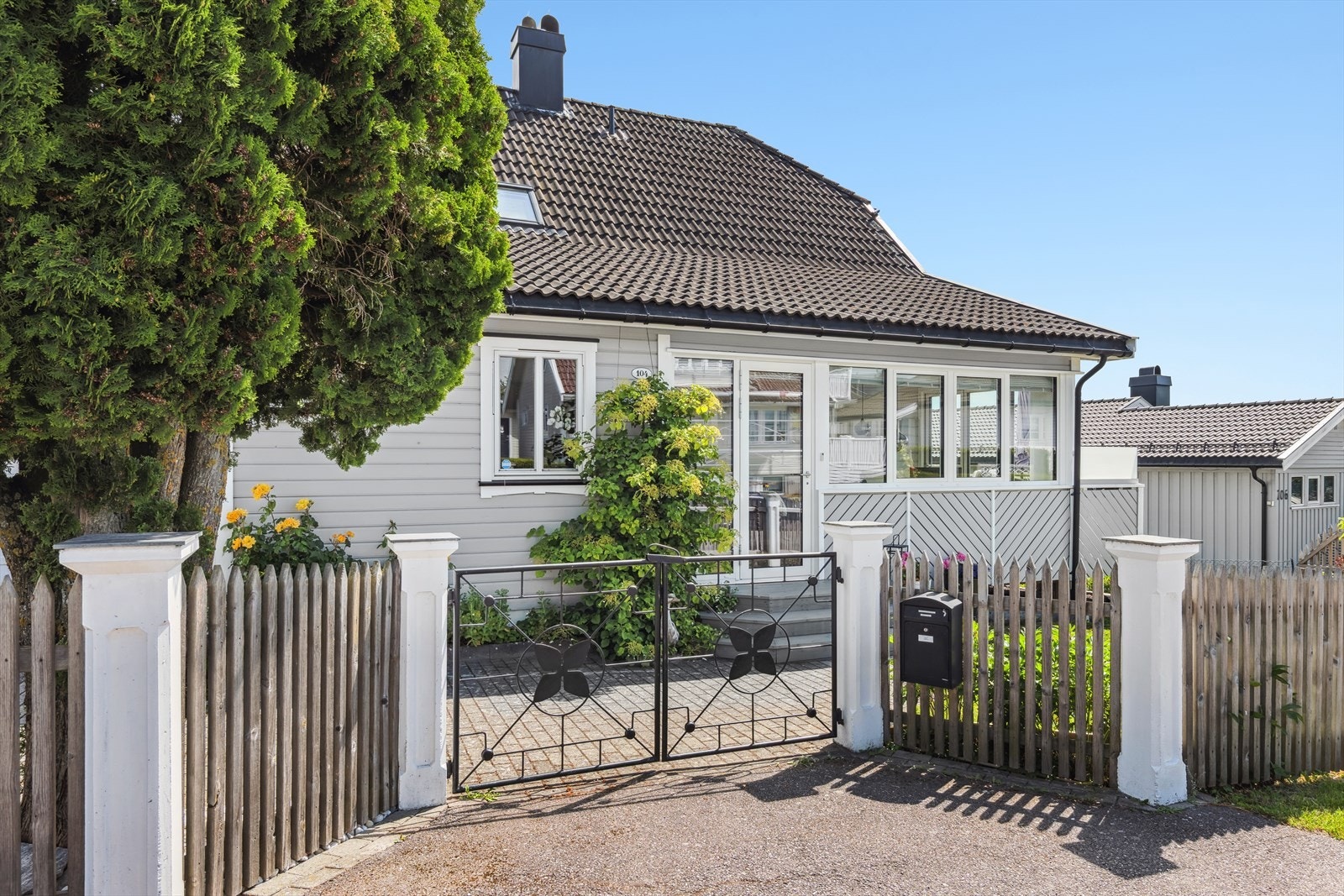 Eiendommen har et flott inngangsparti med smijernsport og pent gjerde med støpte søyler Galleribilde