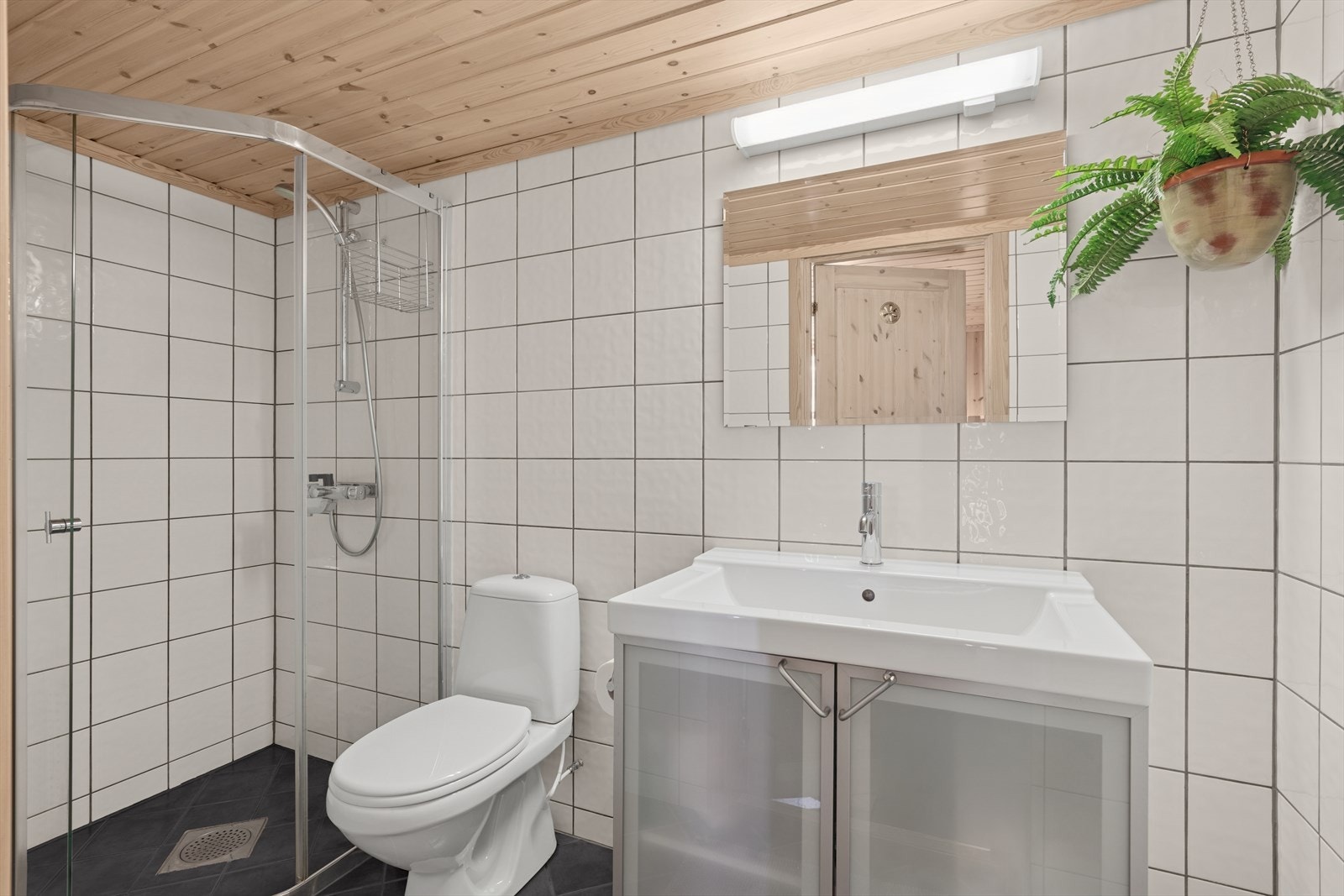 Badet i kjelleren har nedfelt servant, toalett og dusjhjørne. Elektriske varmekabler i gulv. Badet har elektrisk styrt vifte og tilluft i dør. Galleribilde