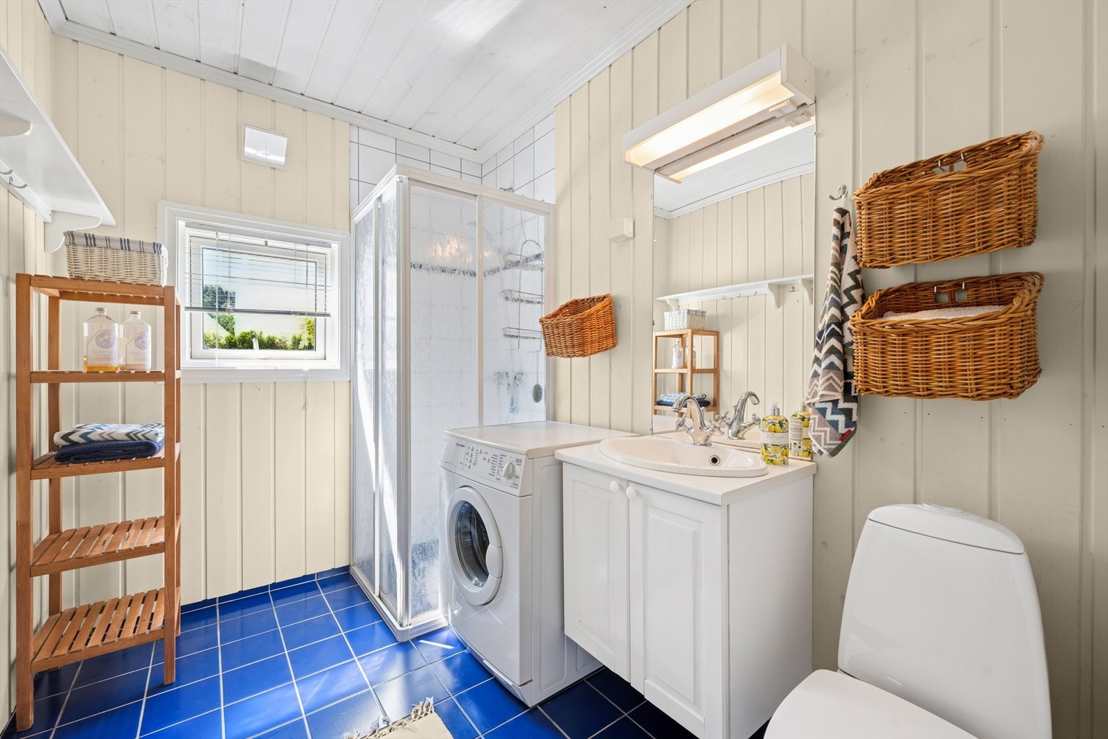 Kombinert bad og vaskerom med dusjnisje, klosett, vask og opplegg til vaskemaskin. Galleribilde