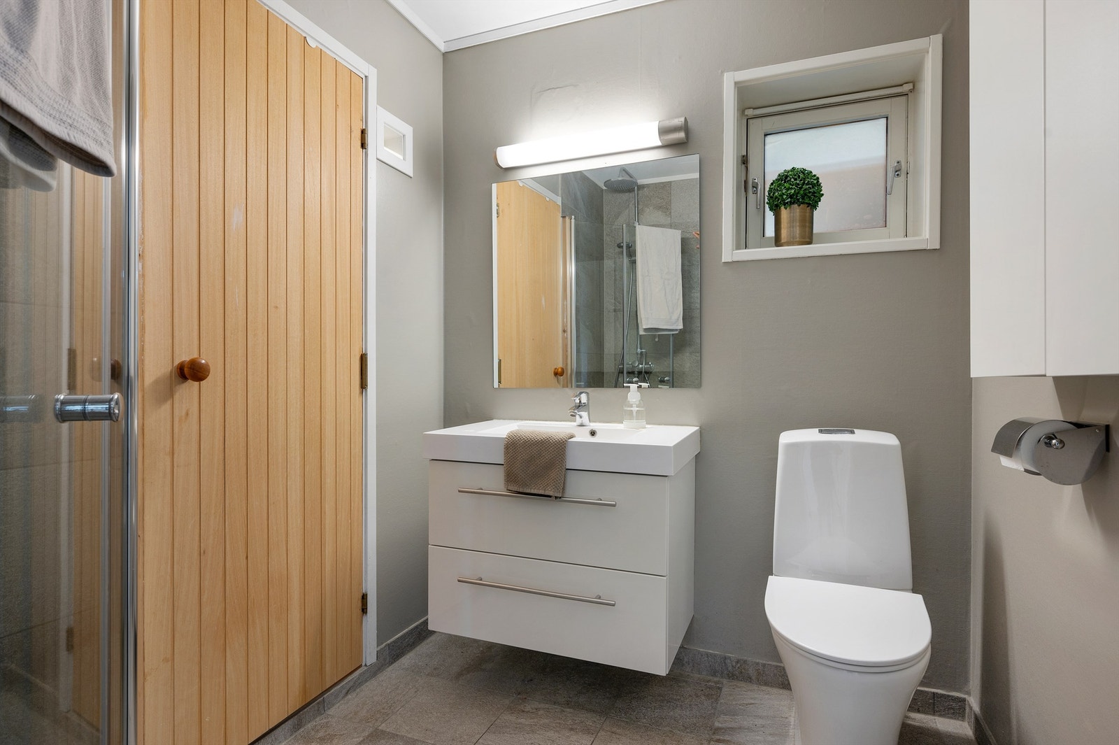 Badet i kjelleretasjen er på 3,5 kvm og er innredet med flislagt gulv med varme, servantskap med speil og lys, dusjhjørne med regndusj og toalett. Galleribilde