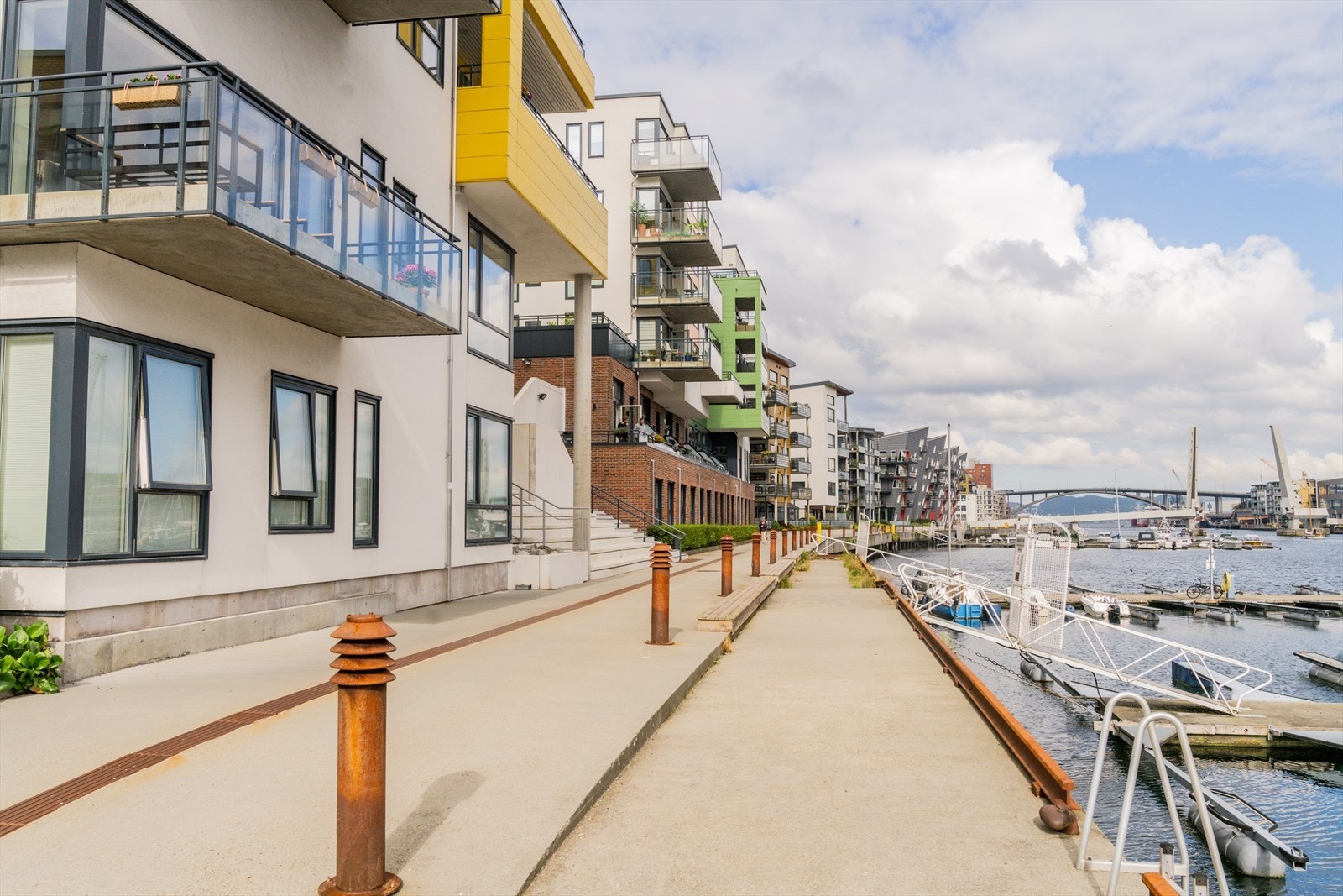 Her kan du rusle langs sjøkanten på en sammenhengende badebrygge, omgitt av moderne boligbygg og maritim stemning. Galleribilde