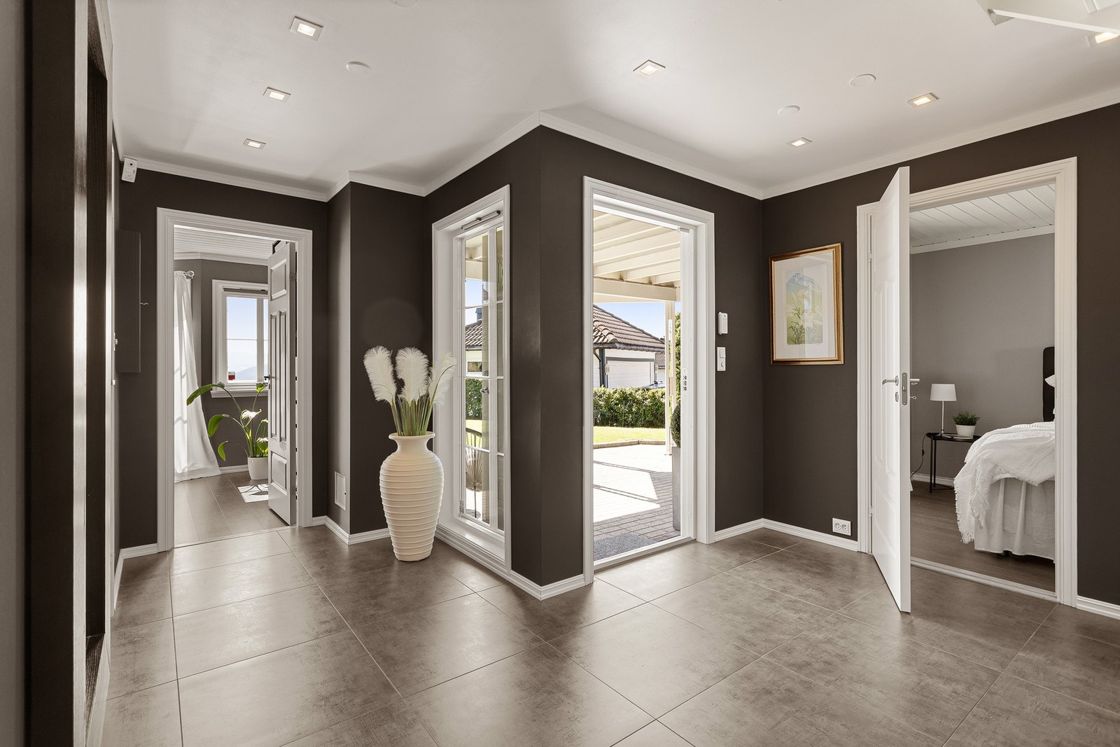 Entreen er innbydende med mørke fliser og varmekabler i gulvet, mørke veggflater, hvitmalt himling med downlights, hvite, profilerte innerdører og dagslys fra sprossevinduer som går helt ned til gulvet. Galleribilde