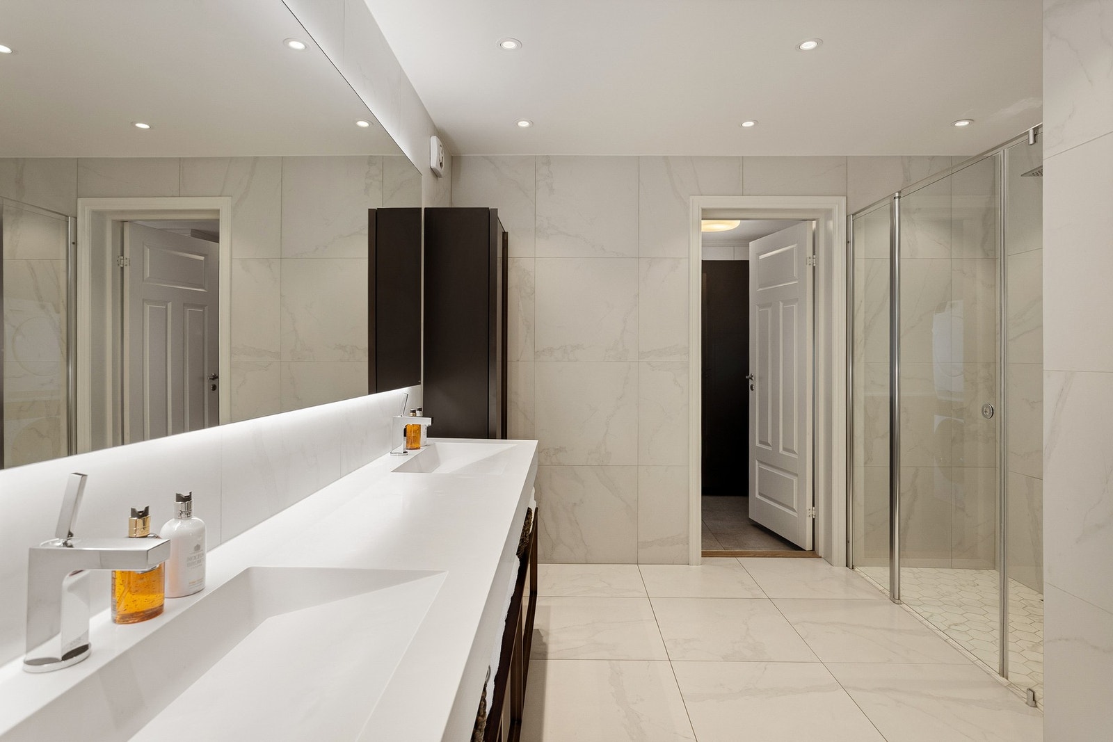 Rommet er utført med lyse, marmorerte fliser på gulv og vegger, gulvvarme og downlights. Galleribilde