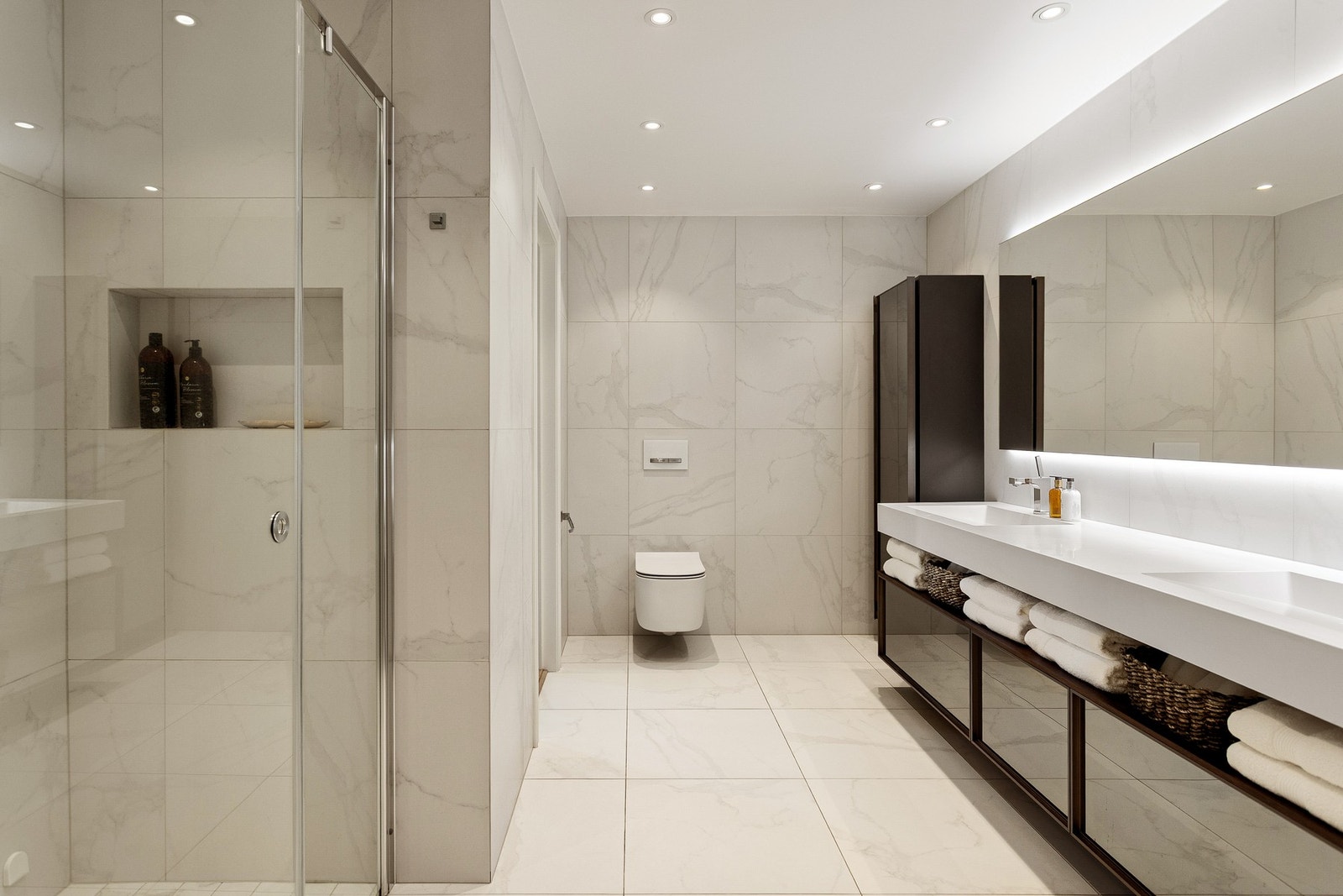 Innredningen er familievennlig og består av en helstøpt dobbelservant over en bred skuffeseksjon i mørkt tre med speilfronter. Galleribilde