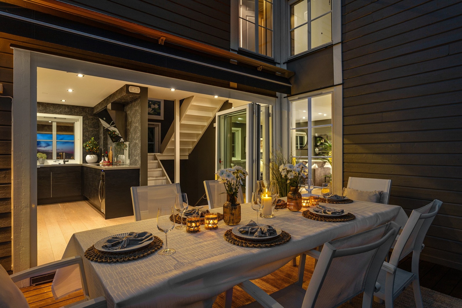 Hele uteplassen har dekke av rillede terrassebord, rekkverk i glass og god plass til komfortable utemøbler, både på åpen del og under tak. Galleribilde