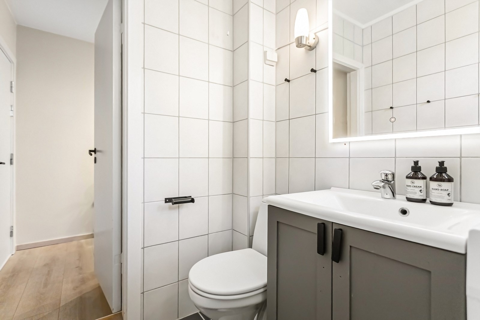 Badet er innredet med benkeskap med servant, innfellbare dusjdører i glass, toalett og opplegg for vaskemaskin Galleribilde