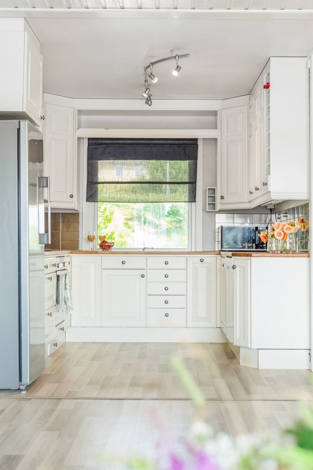 Kjøkkeninnredningen er i en vinkel med malte, profilerte fronter og en benkeplate i heltre Galleribilde