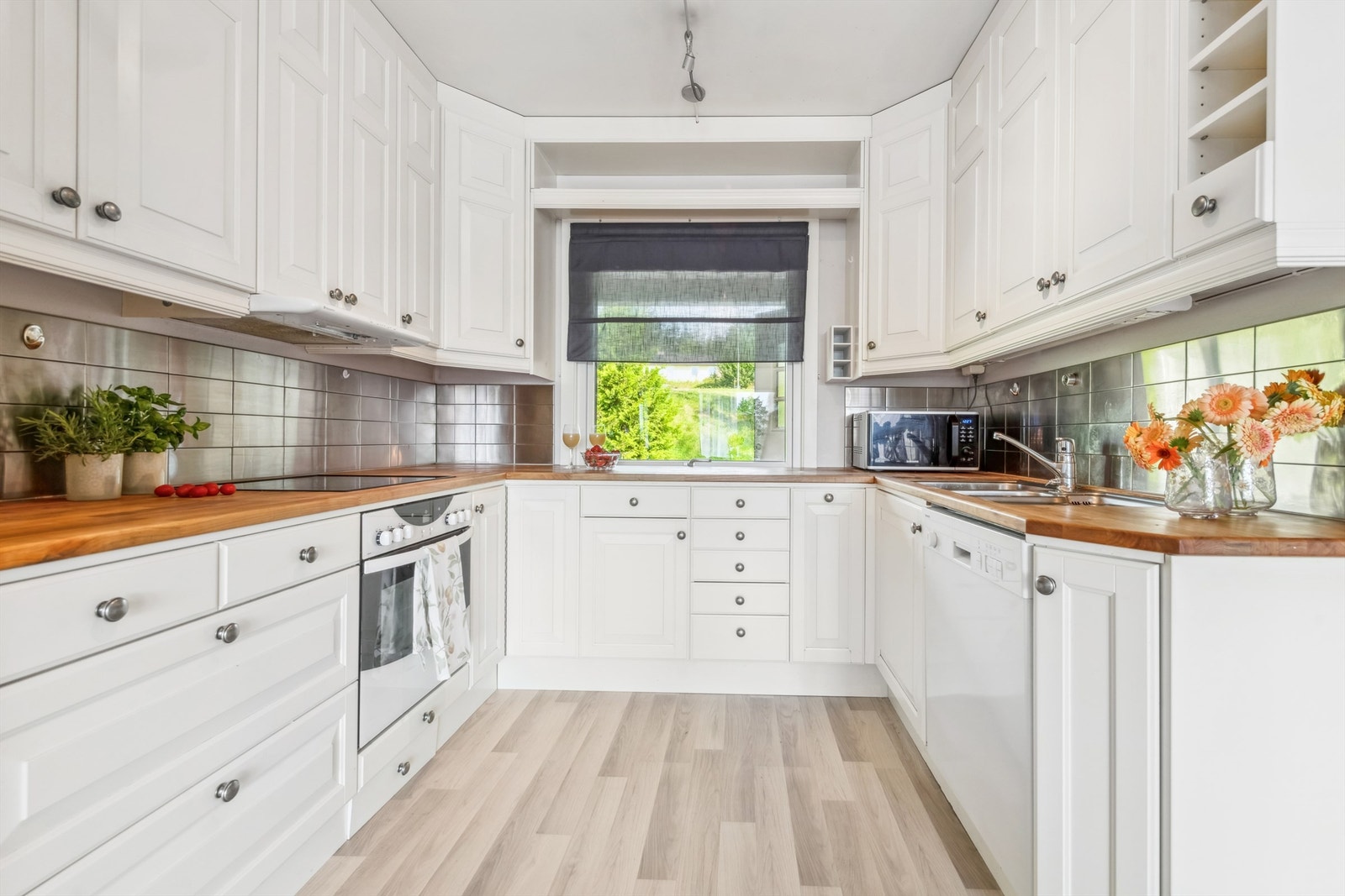 Pent kjøkken med heltre benkeplater og integrert platetopp og stekovn Galleribilde