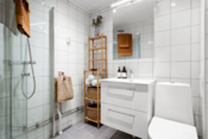 Badets Innredning består av en servant med slette fronter, gulvstående toalett og et dusjhjørne med svingbare glassdører Galleribilde