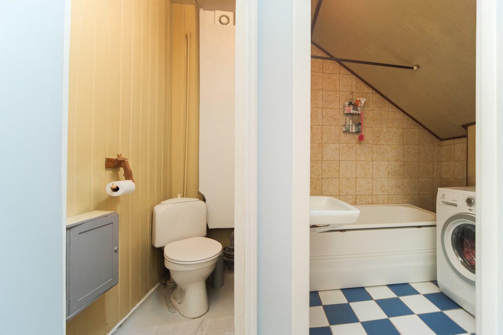 Baderommet har varme i gulv og er utstyrt med badekar, servant, opplegg for vaskemaskin og benkeskap med glatte fronter Galleribilde