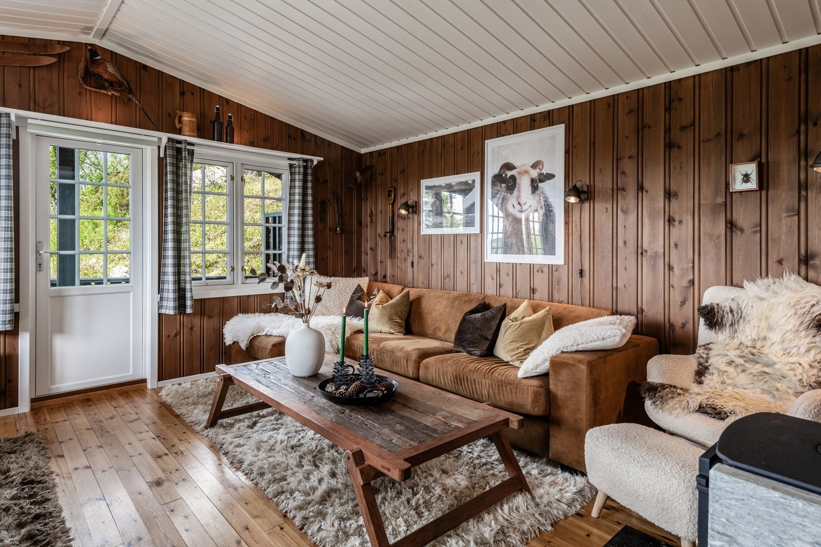 Koselig stue med tregulv, beiset panel på vegger og lysmalt himling. Galleribilde