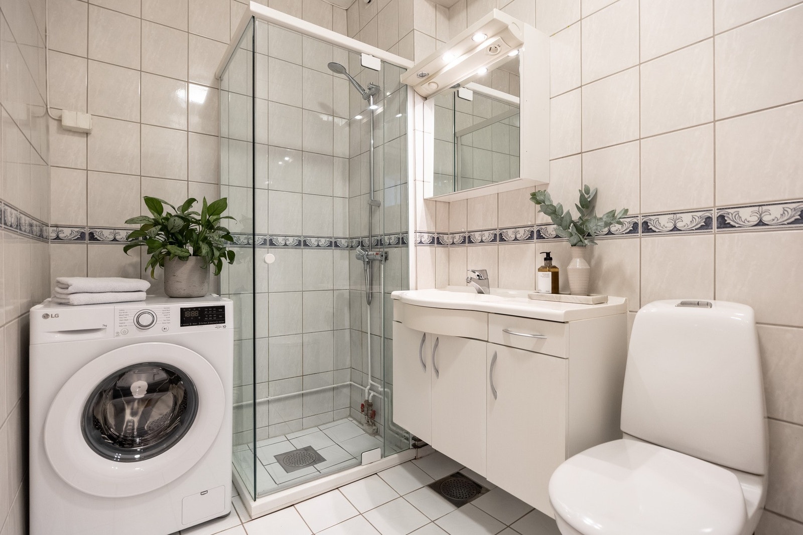 Lyst baderom med opplegg for både tørketrommel og vaskemaskin. Galleribilde