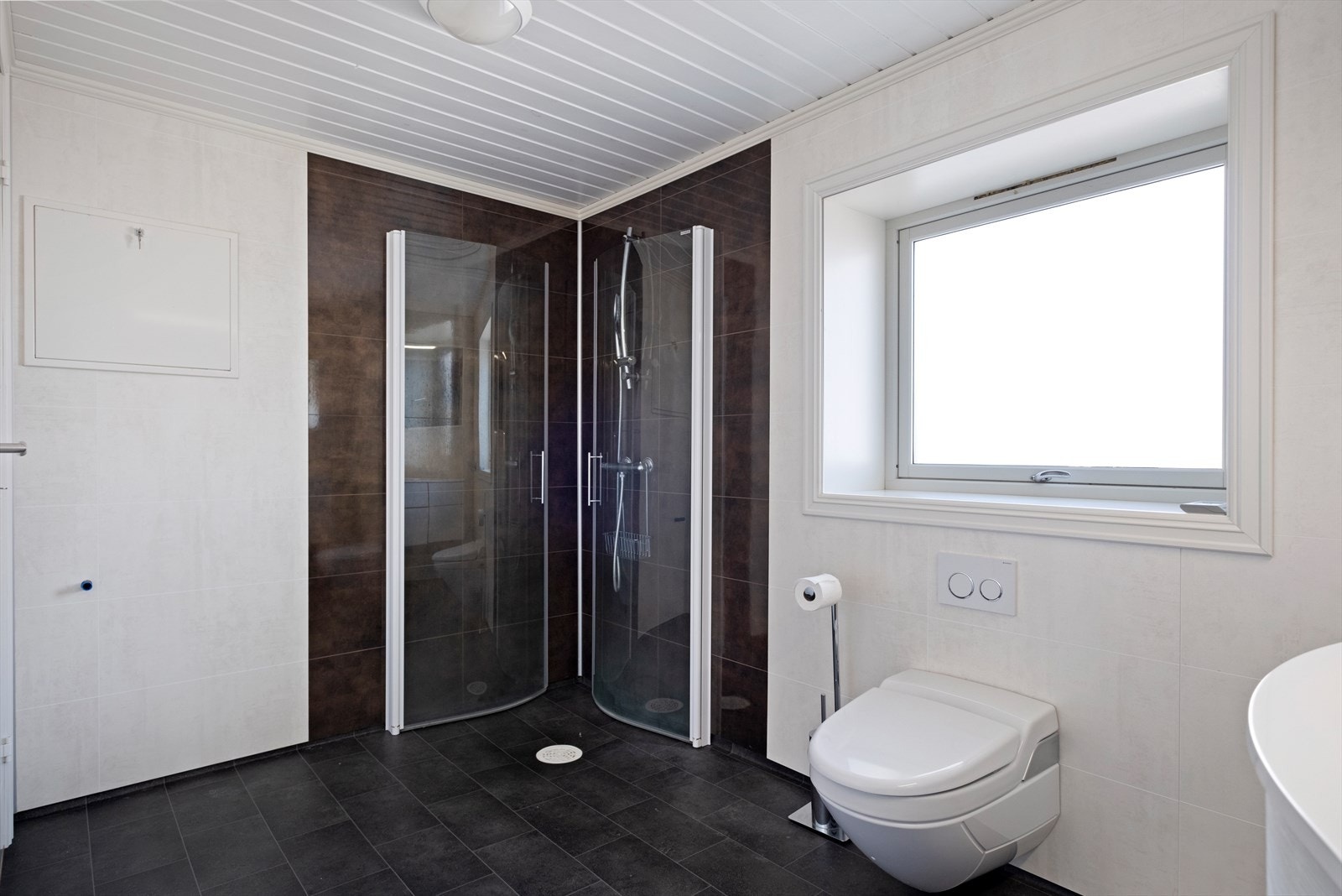 Badet er utstyrt med vegghengte dusjdører, vegghengt wc og varmekabler på gulv Galleribilde