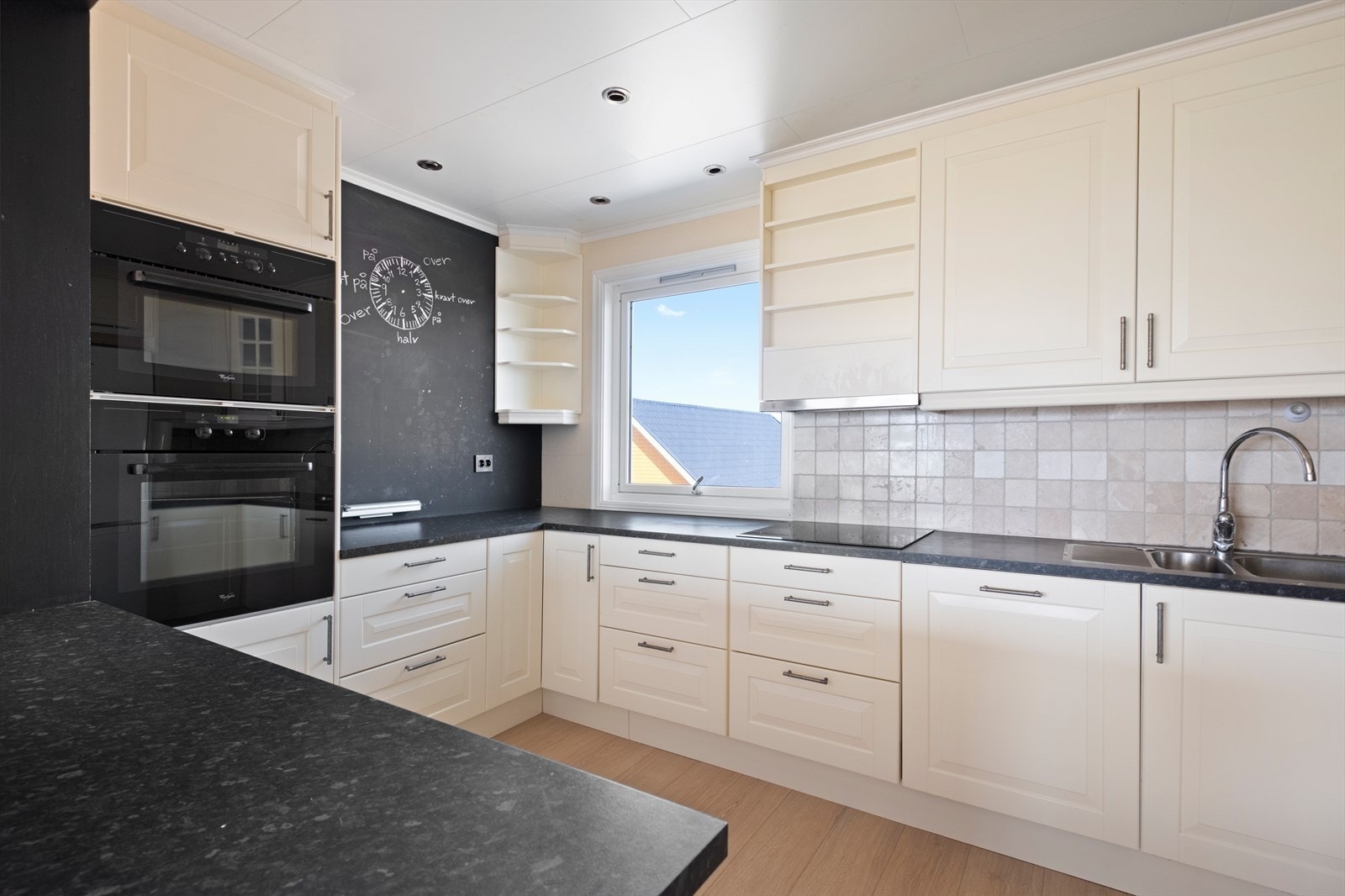 Det er fliser på vegg mellom overskap og underskap Galleribilde