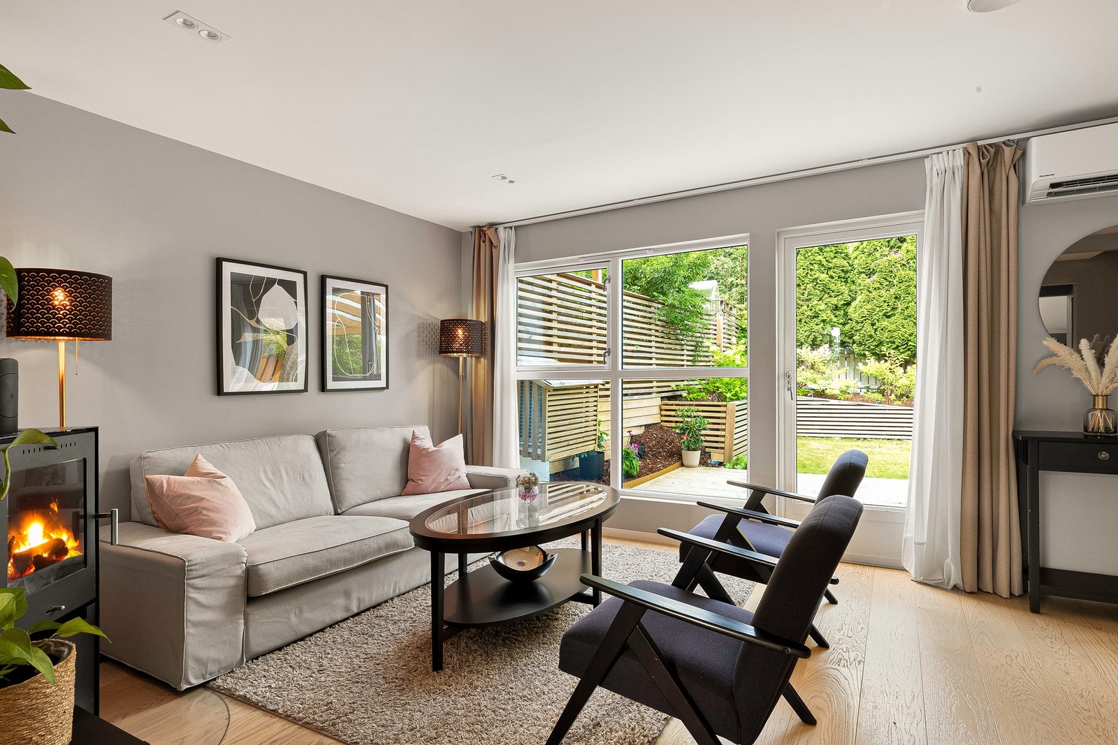 Stuen er lys med store vinduer og utsikt til hagen Galleribilde