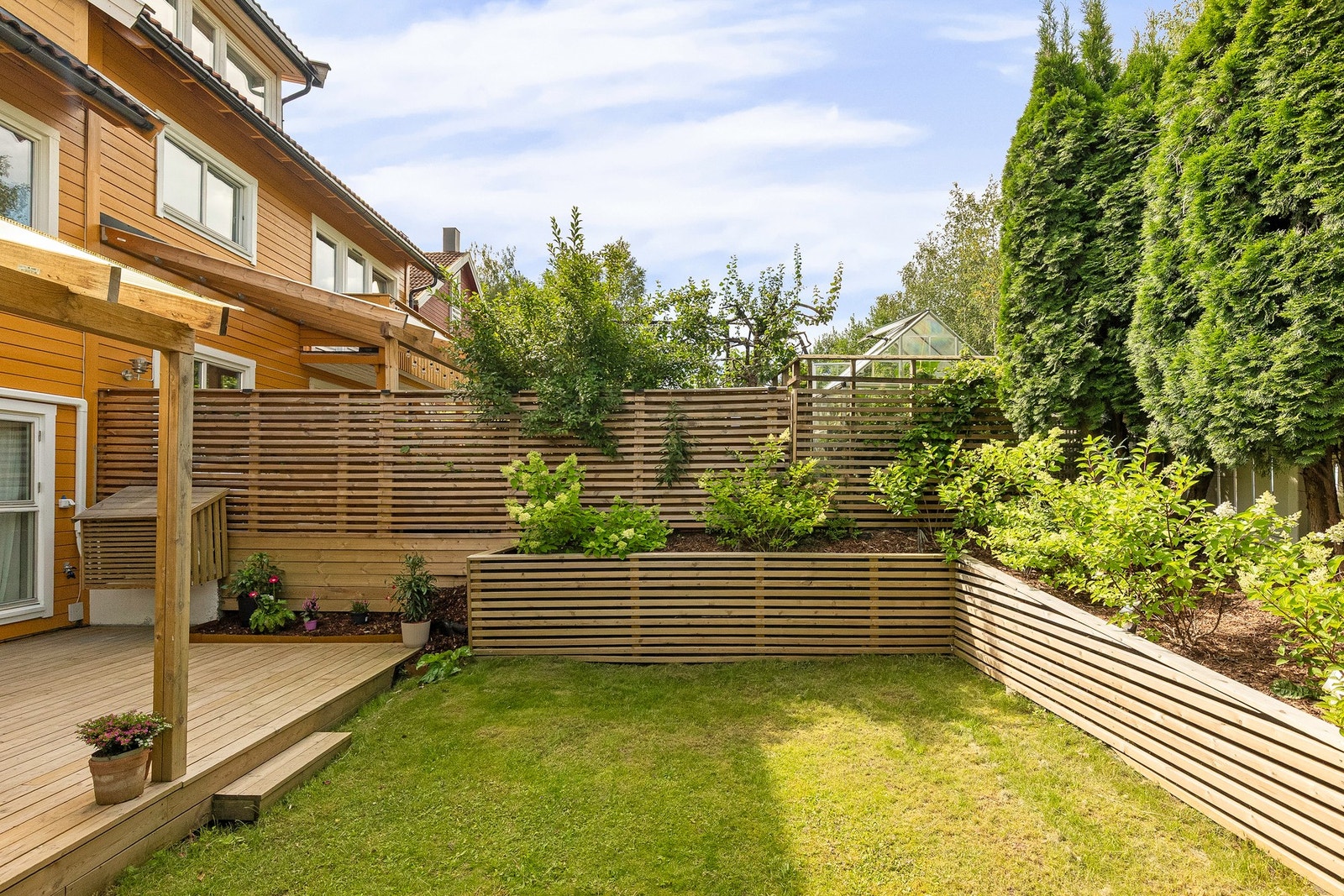 Moderne levegg mot nabo og blomsterbedd innramning og busker som skjermer for innsyn Galleribilde