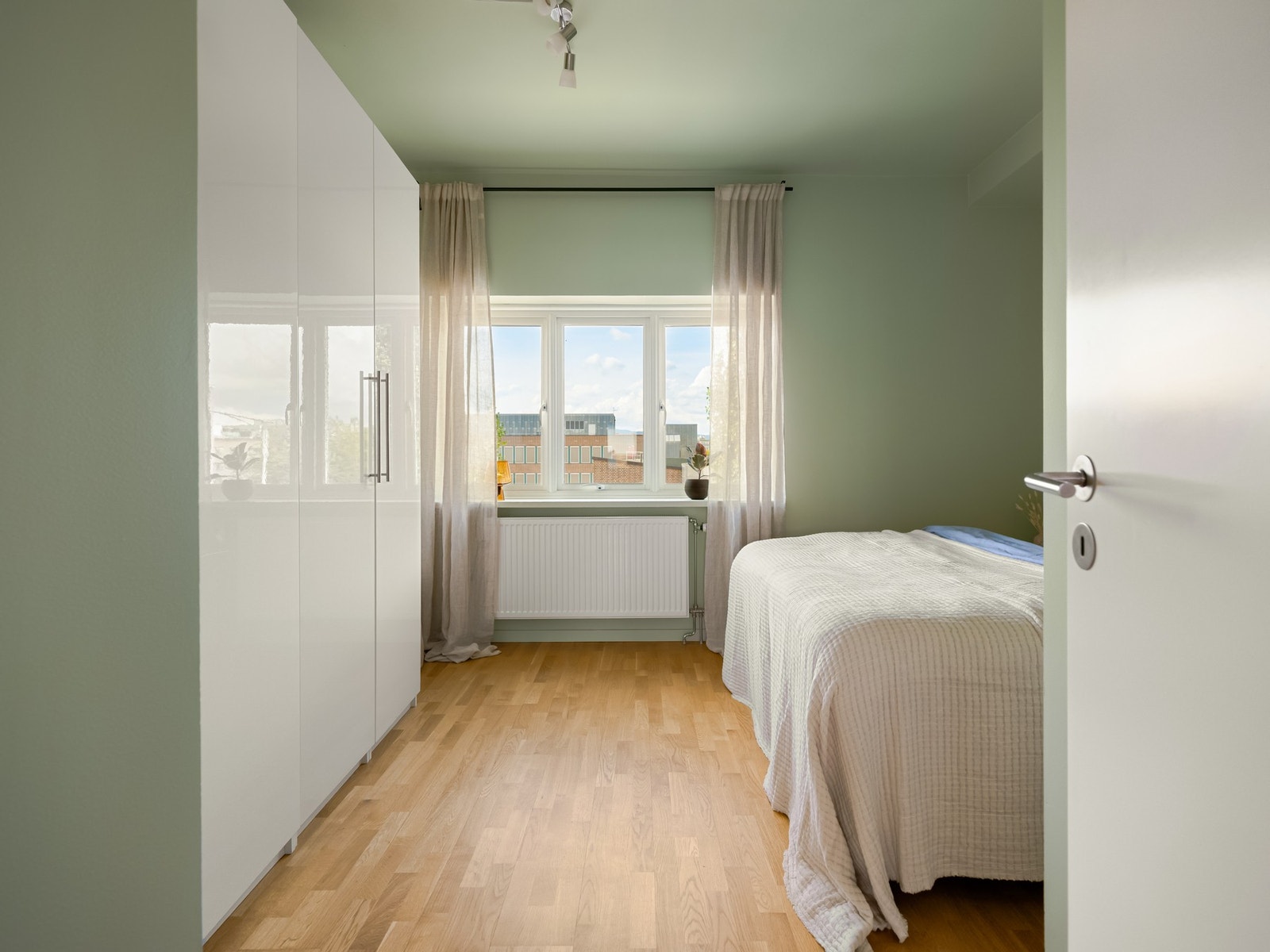 Fra stuen går vi videre inn mot soverommet. Leiligheten ligger høyt og luftig i byggets 3. etasje uten innsyn fra veien utenfor eller forbipasserende. Galleribilde