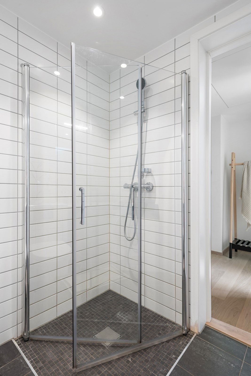 Badet er innredet med vegghengt toalett, baderomsinnredning med speilskap og dusjhjørne med innfellbare glassdører Galleribilde