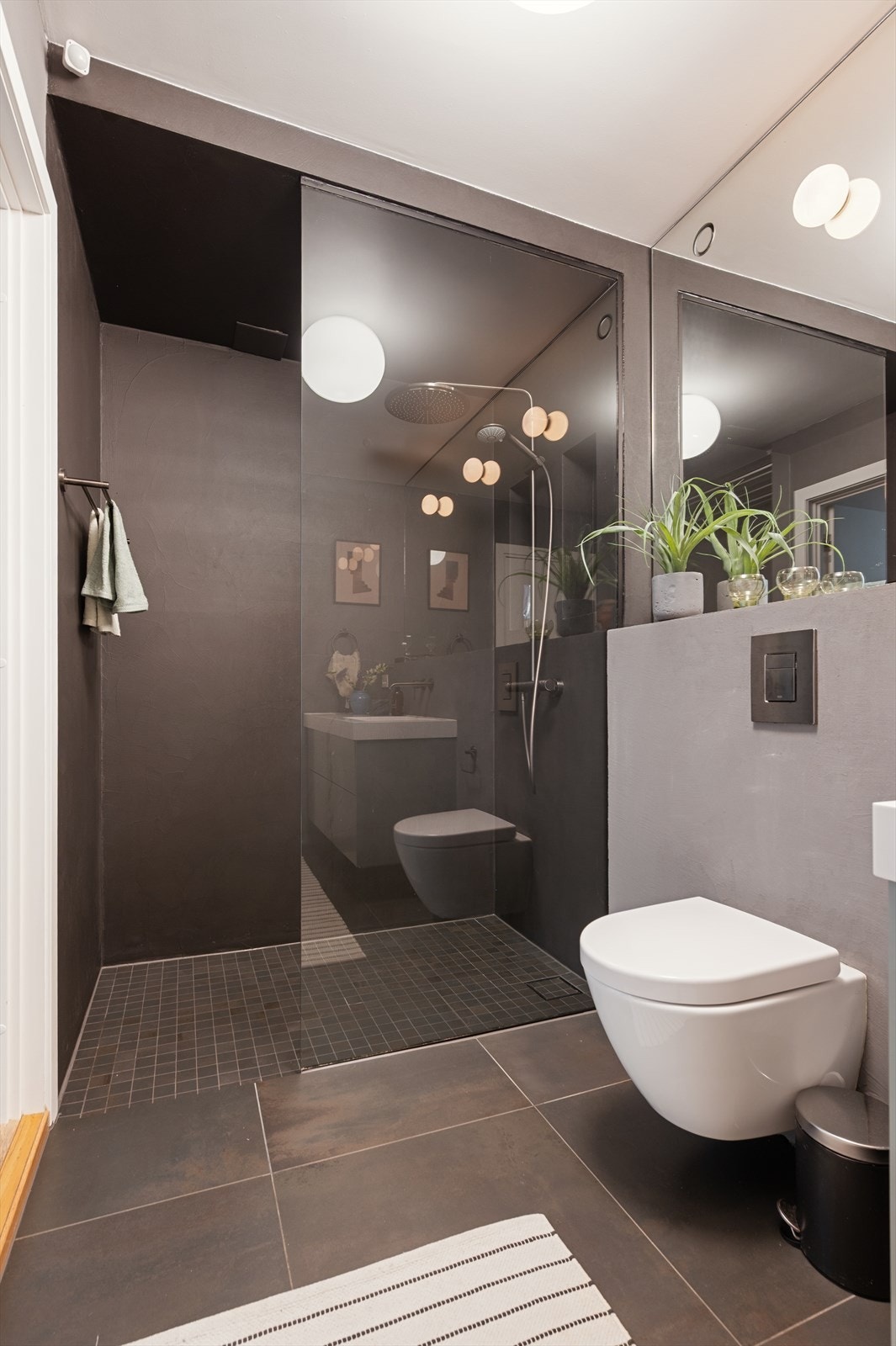 Vegghengt toalett med innebygget sisterne og dusjhjørne med både regn- og hånddusj. Galleribilde