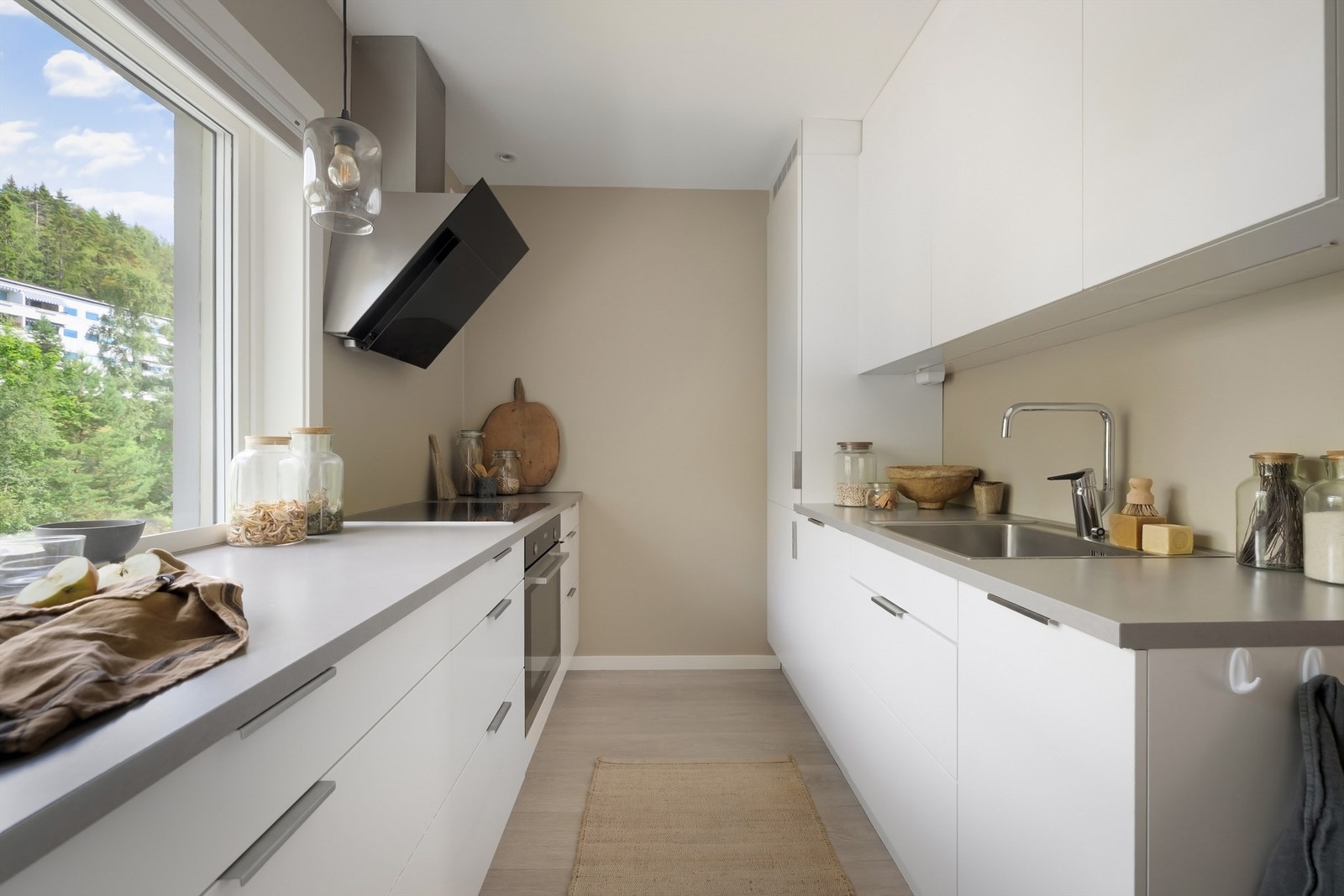 Delikat kjøkkeninnredning med hvite, glatte fronter, benkeplate av laminat og nedfelt oppvaskkum med ett-greps armatur Galleribilde