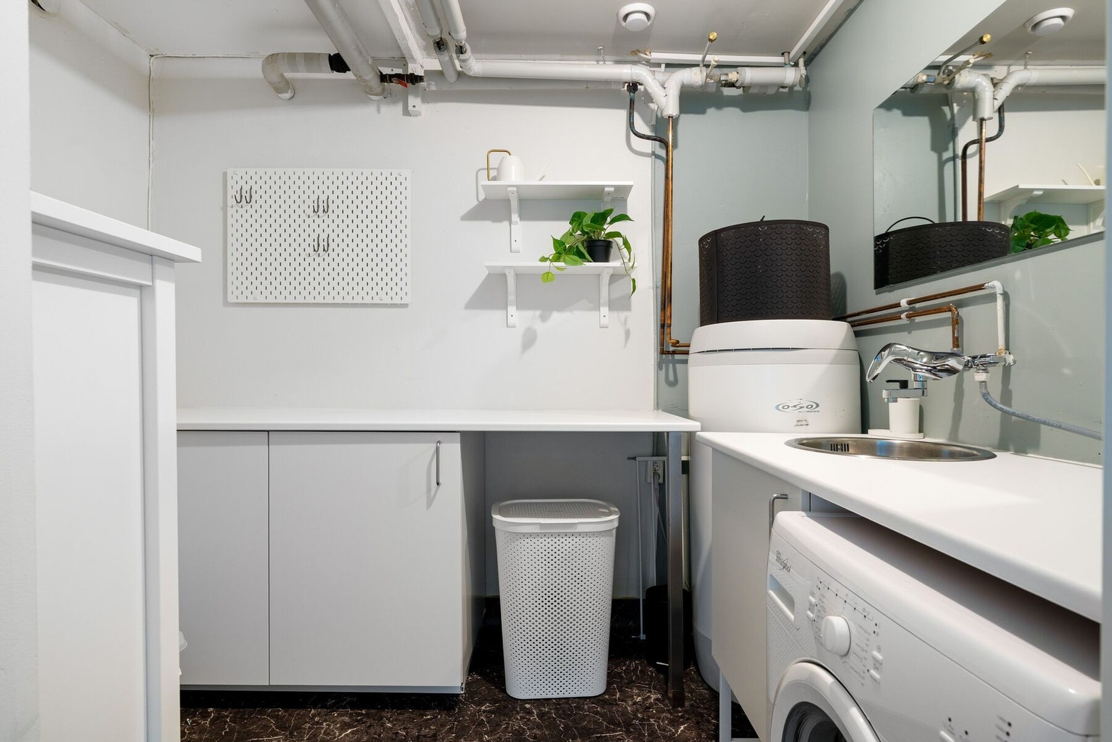 Praktisk vaskerom utstyrt med opplegg for vaskemaskin, utslagsvask, hovedstoppekran og varmtvannstank. Galleribilde