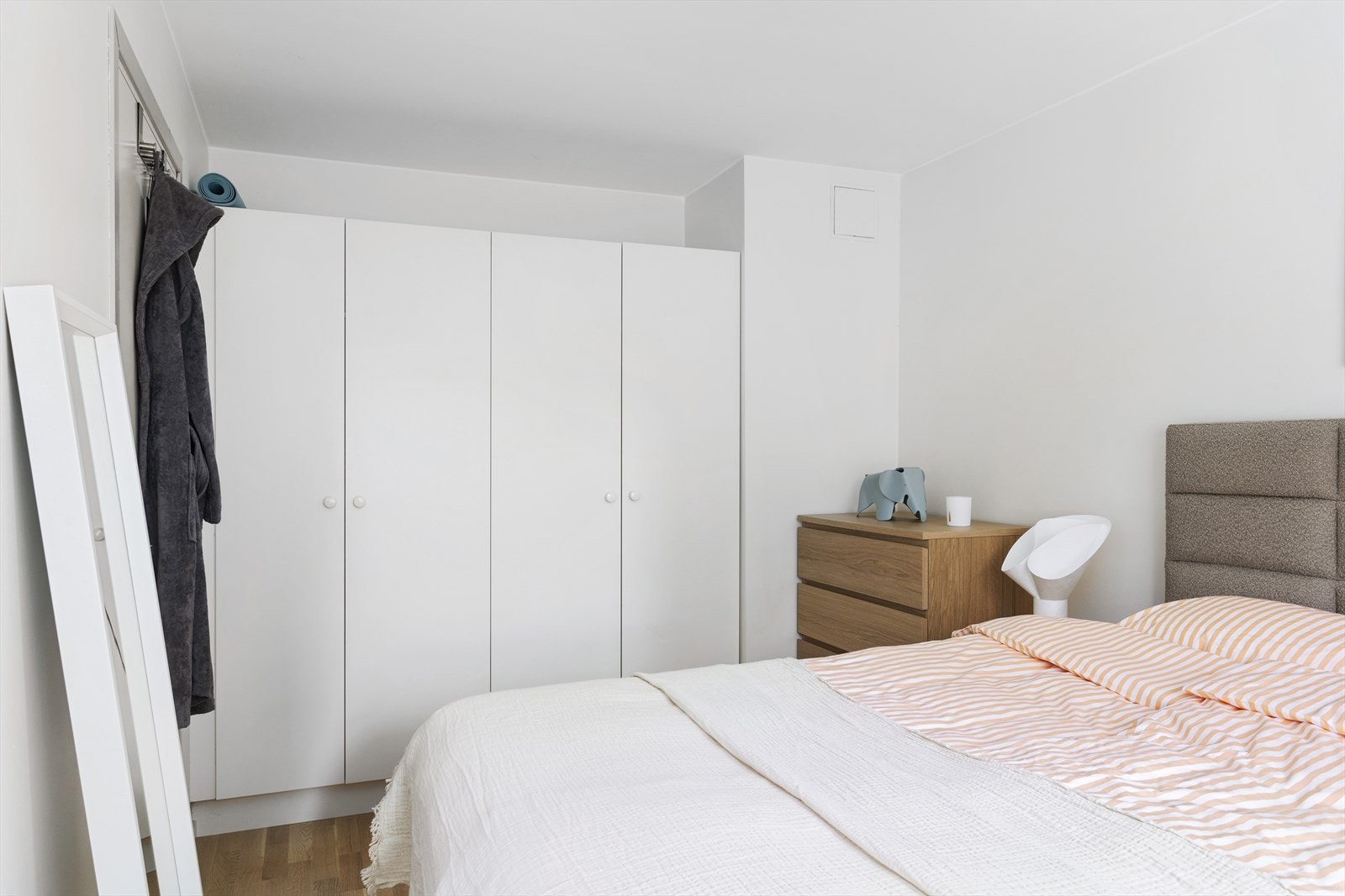 Det medfølger et romslig og praktisk garderobeskap med slette, hvite fronter som gir rikelig med oppbevaringsplass. Galleribilde