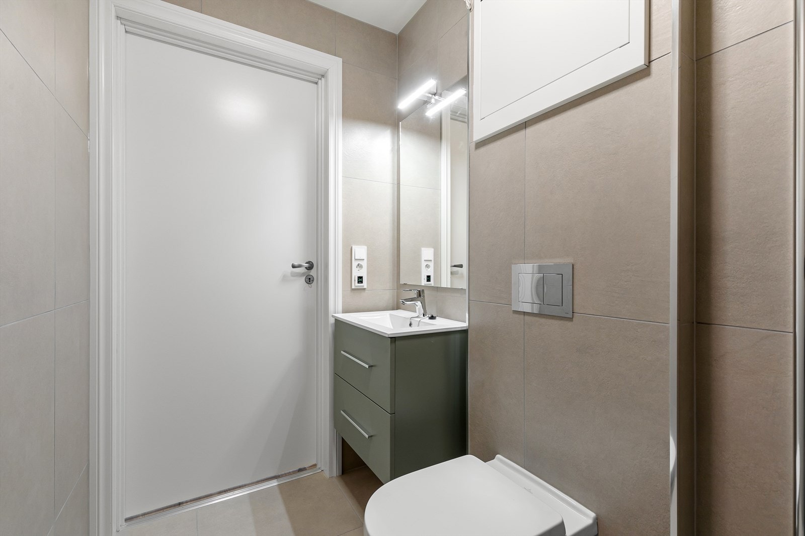 Badet er utstyrt med vegghengt toalett, servant med innreiing og dusj med innfellbare dører. Galleribilde